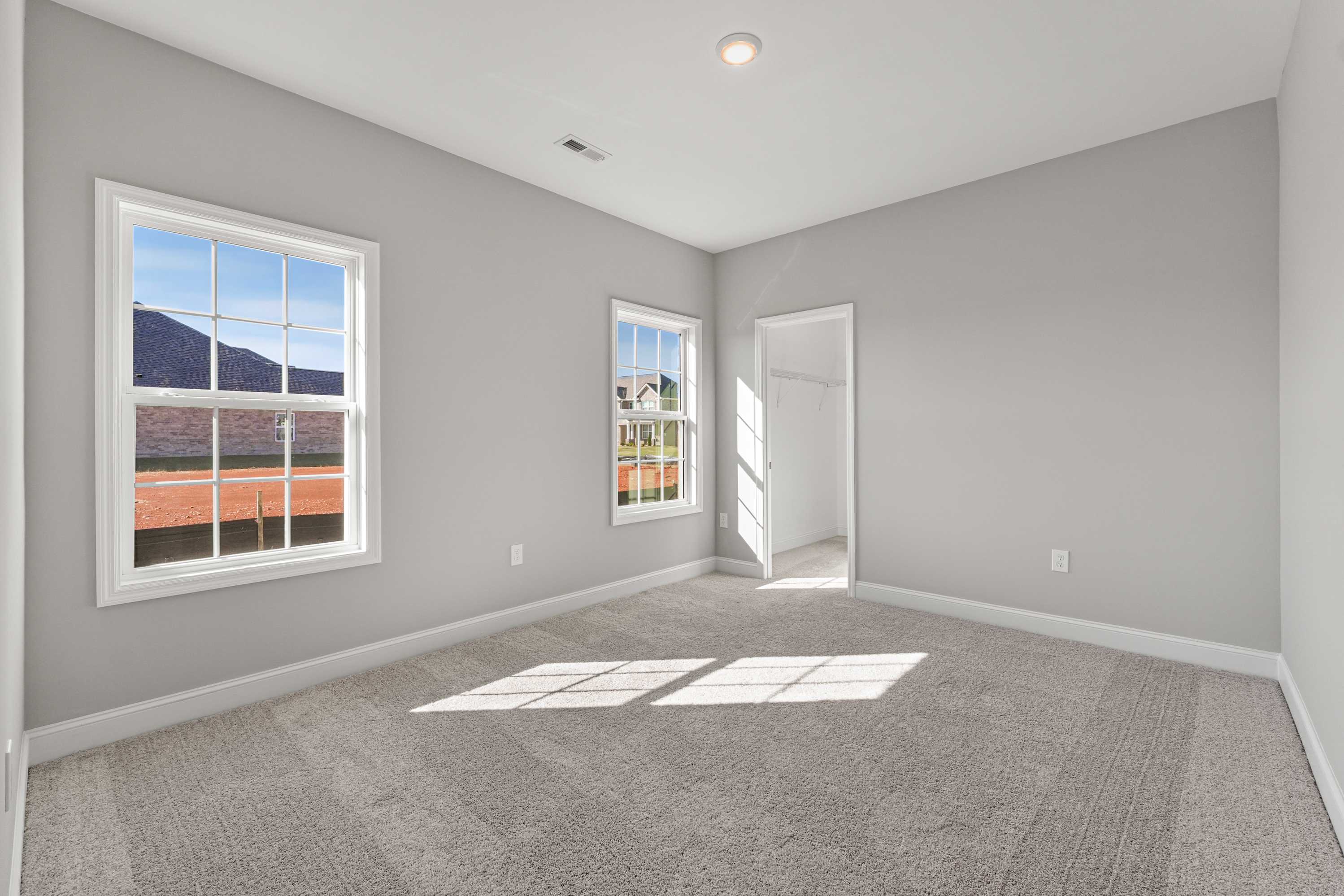 Spacious Valencia bedroom interior with light gray walls, neutral carpet, double windows showcasing mountain views