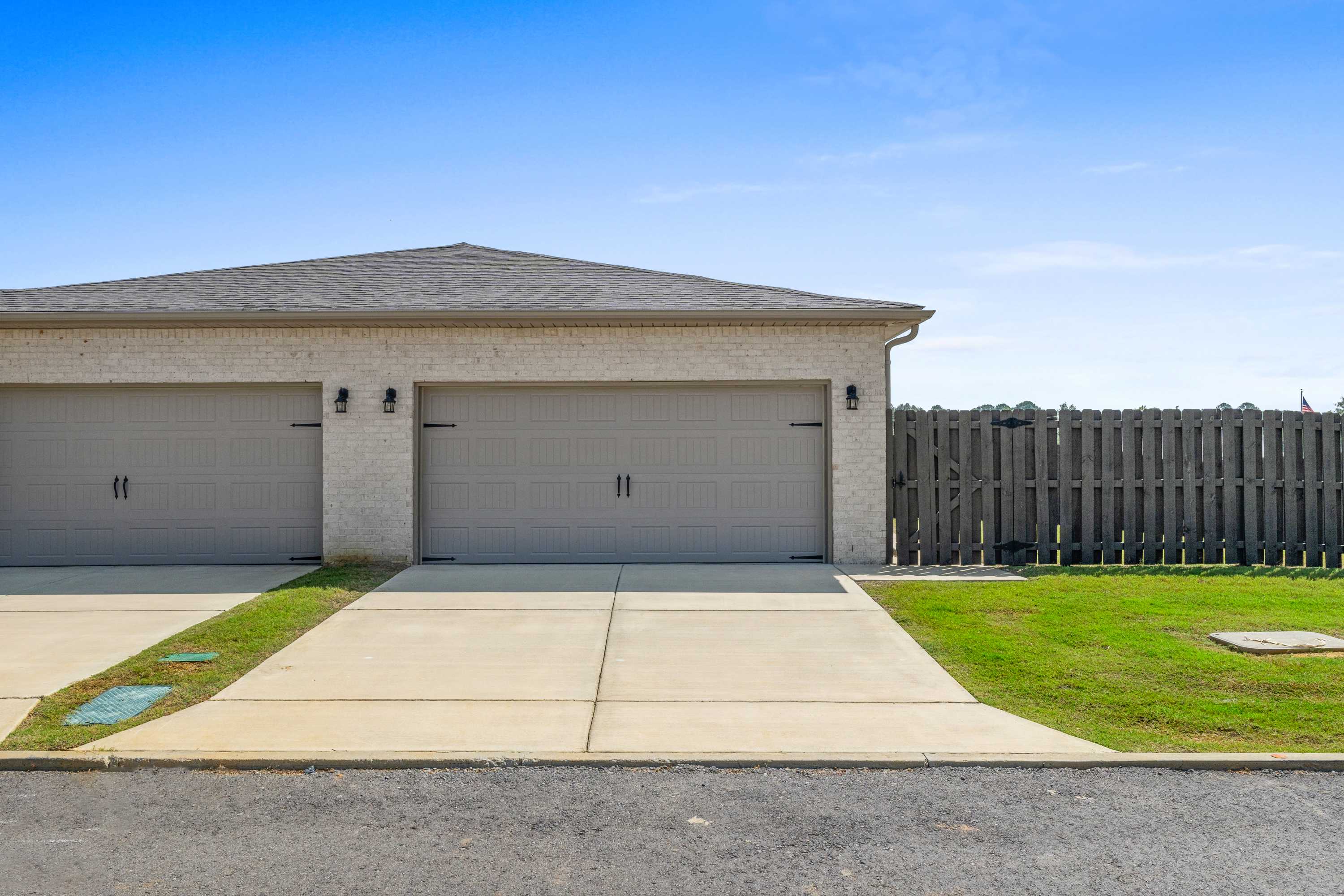 Two-car garage on modern home exterior at The Retreat at Cain Park in Hartselle Alabama by Davidson Homes with wooden fence and driveway