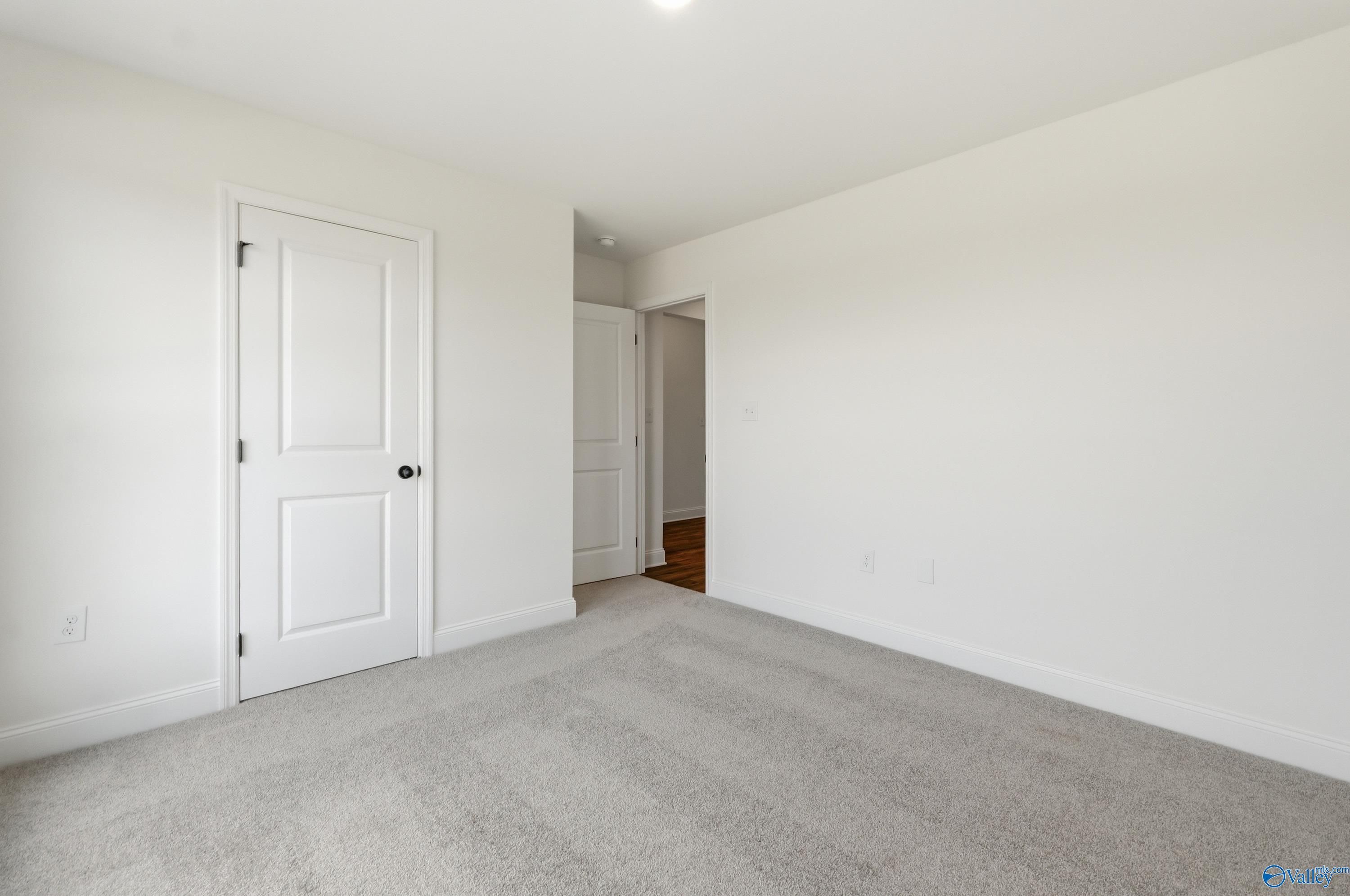 Bright, carpeted bedroom with white walls and doors in The Franklin floor plan at Heritage Lakes, New Market, Alabama.