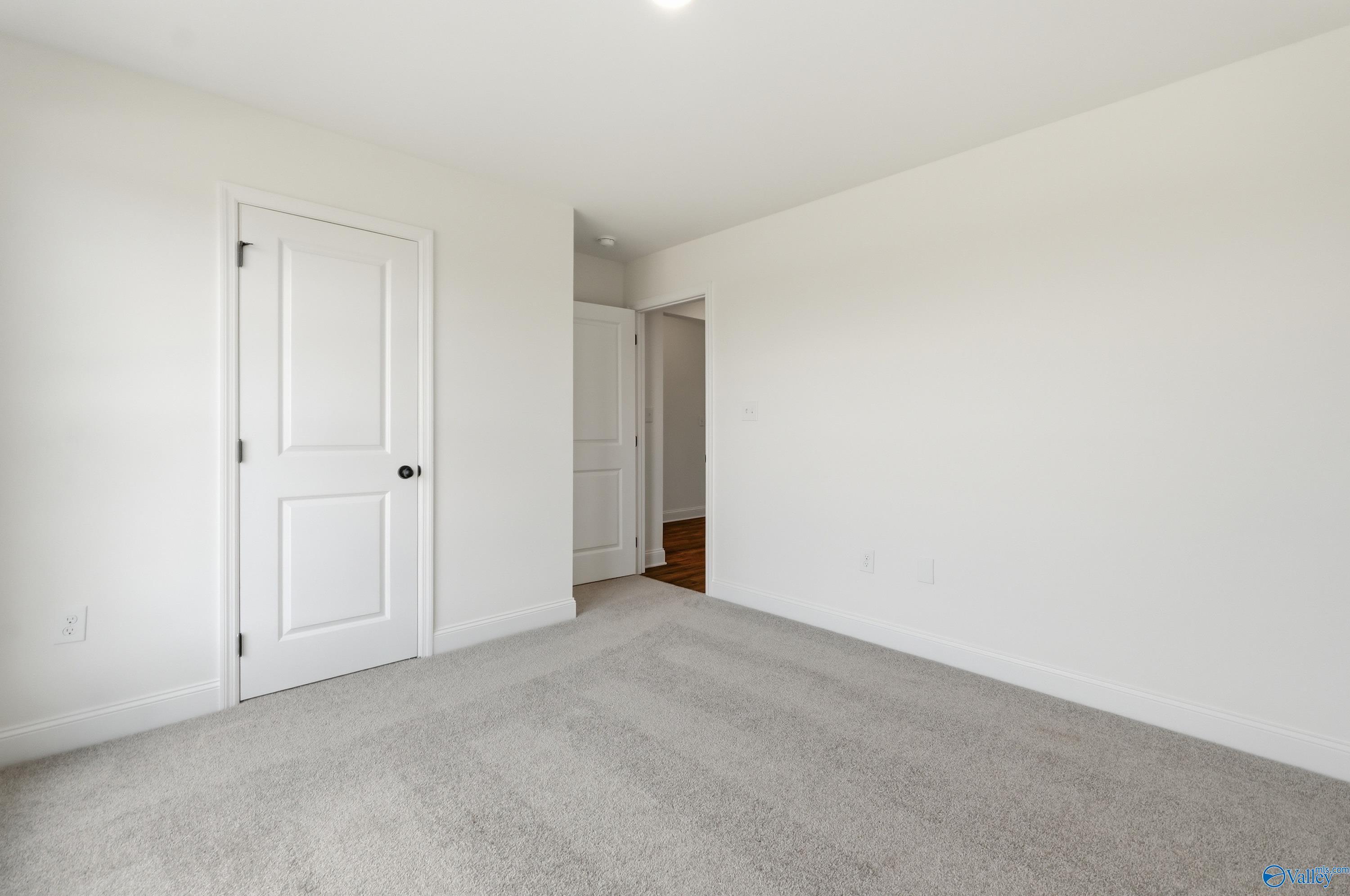 Bright, carpeted bedroom with white walls and doors in The Franklin floor plan at Heritage Lakes, New Market, Alabama.