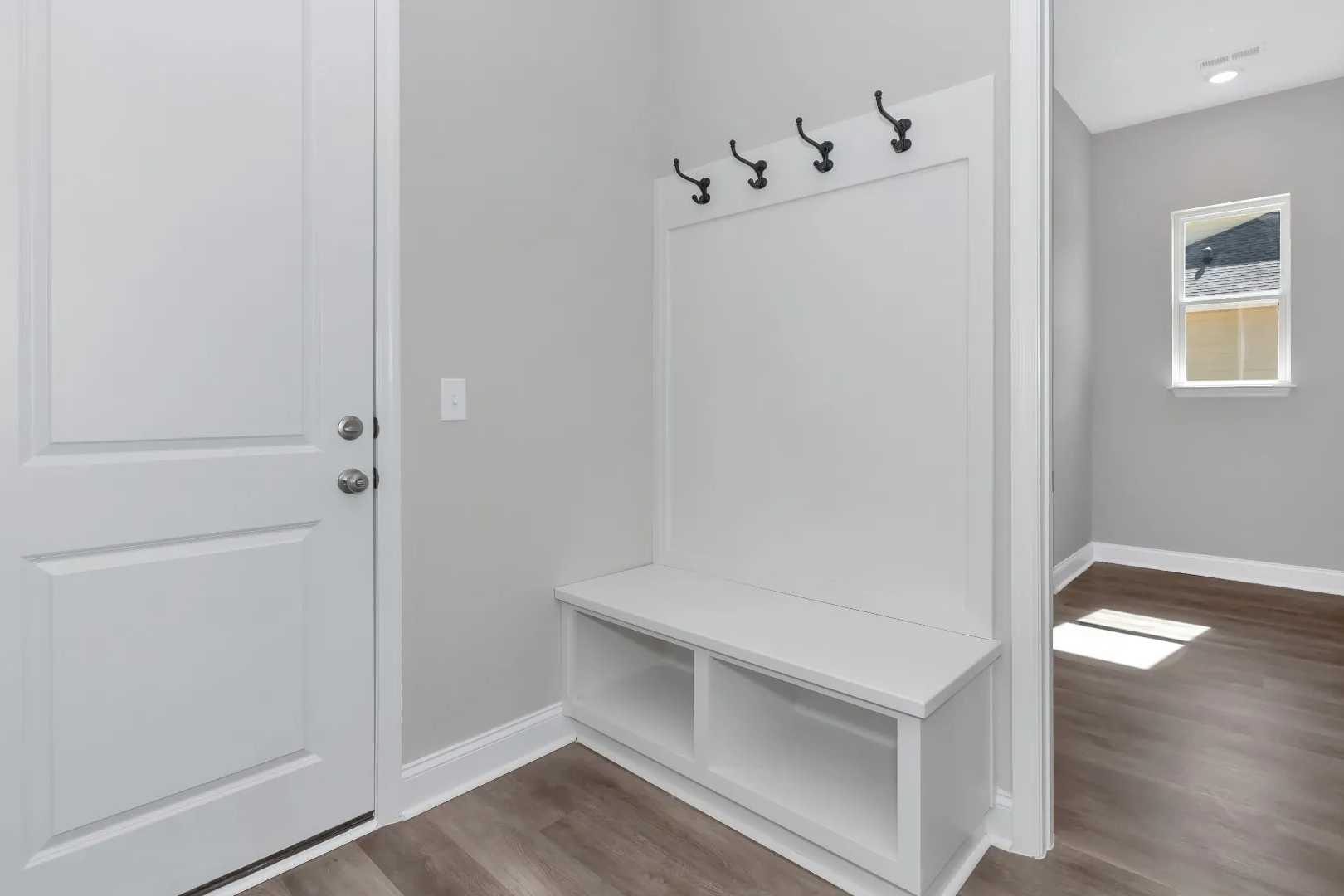 Spacious mudroom in The Arcadia M with white built-in bench, coat hooks, storage shelves, and hardwood floors
