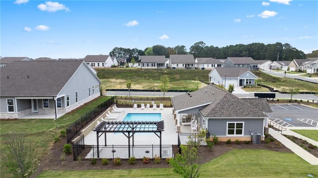 Aerial view of Kelly Preserve community pool with pergola, lounge chairs, and clubhouse amid Davidson Homes in Loganville, Georgia