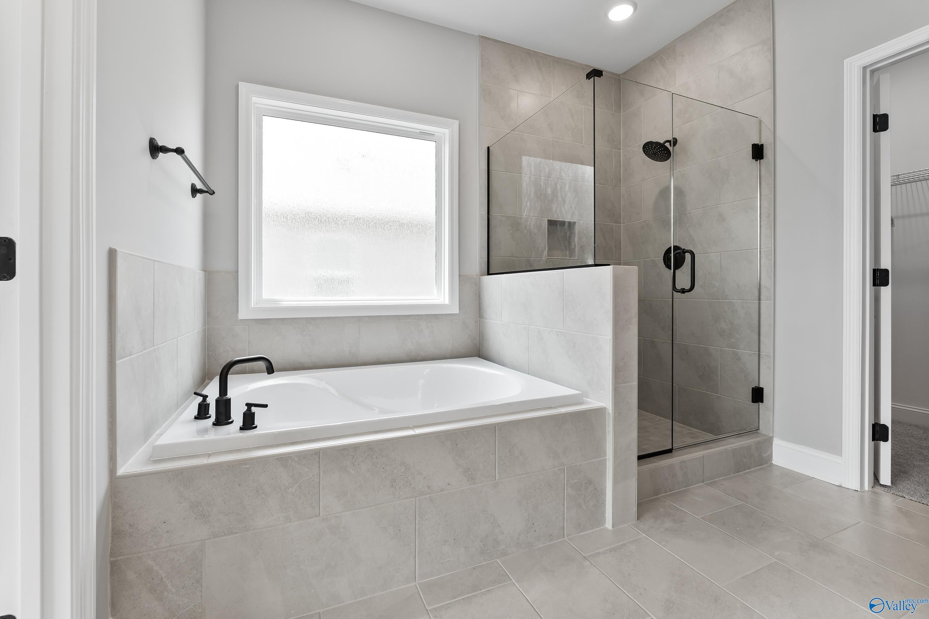 Modern master bathroom with freestanding tub, glass shower, and black fixtures in Davidson Homes The Montgomery B With Bonus, Toney, Alabama