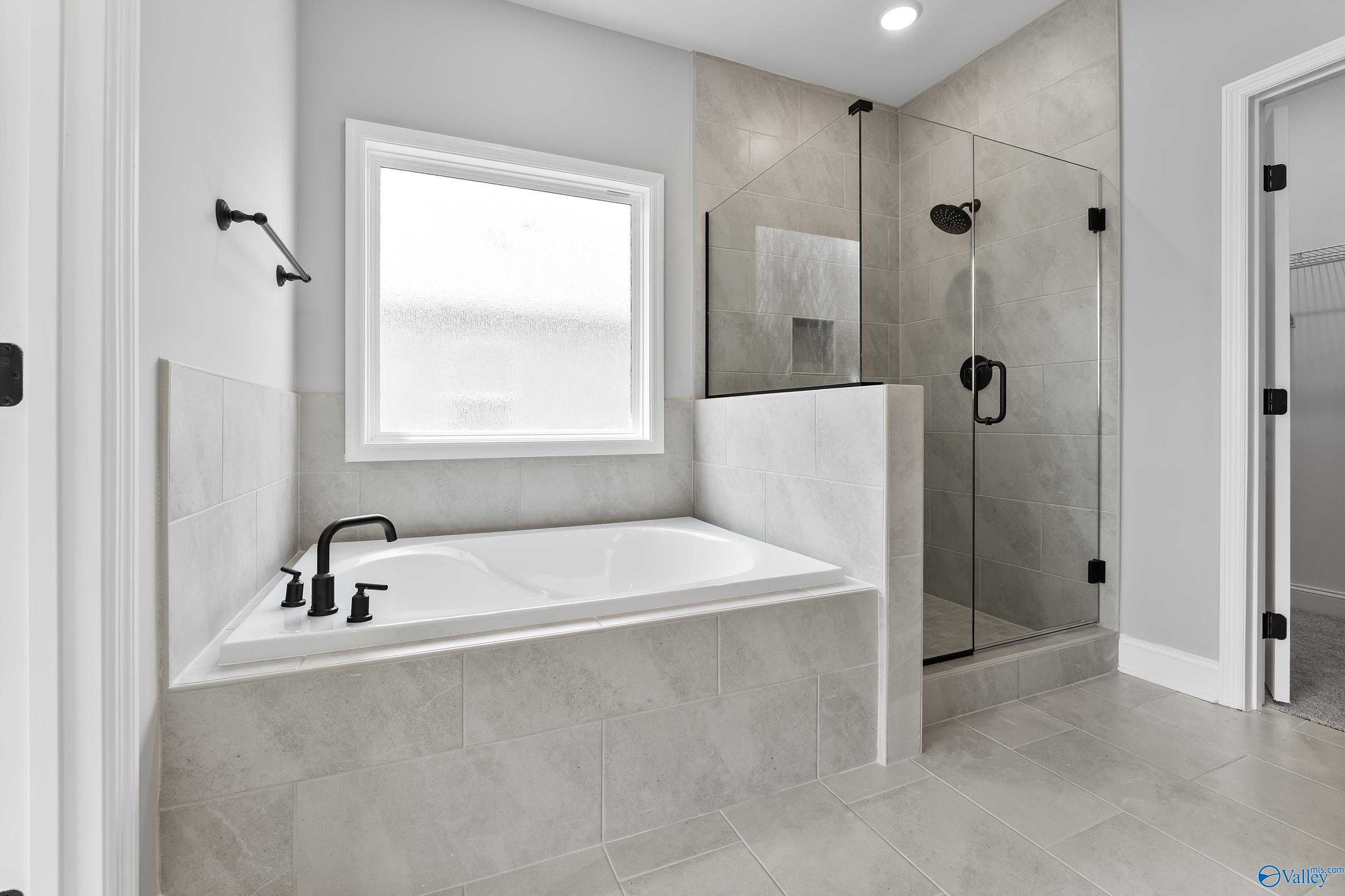 Modern master bathroom with freestanding tub, glass shower, and black fixtures in Davidson Homes The Montgomery B With Bonus, Toney, Alabama