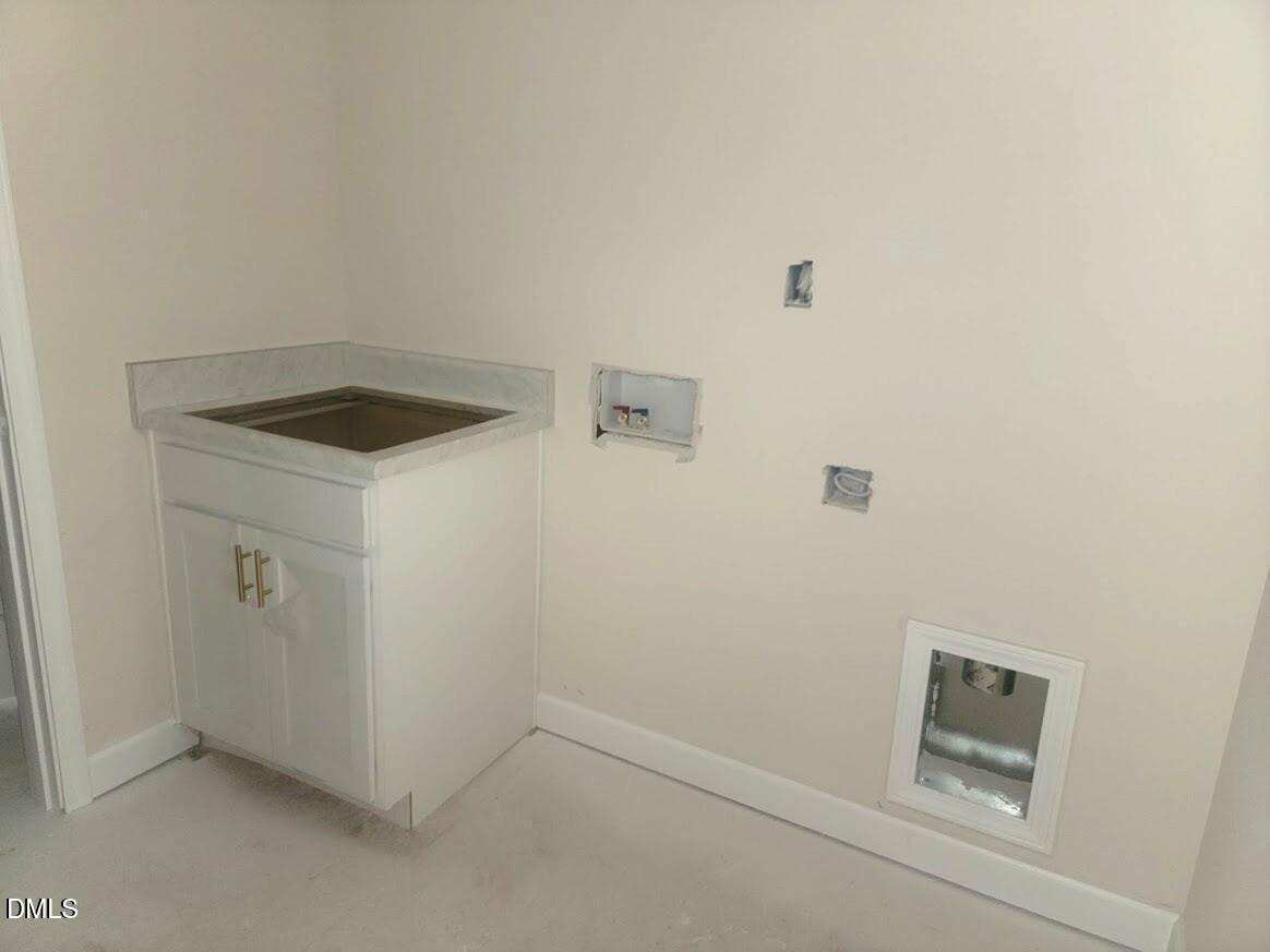 Modern laundry room with white utility sink, washer/dryer hookups, and pet door in Davidson Homes The Cypress B II, Angier, NC