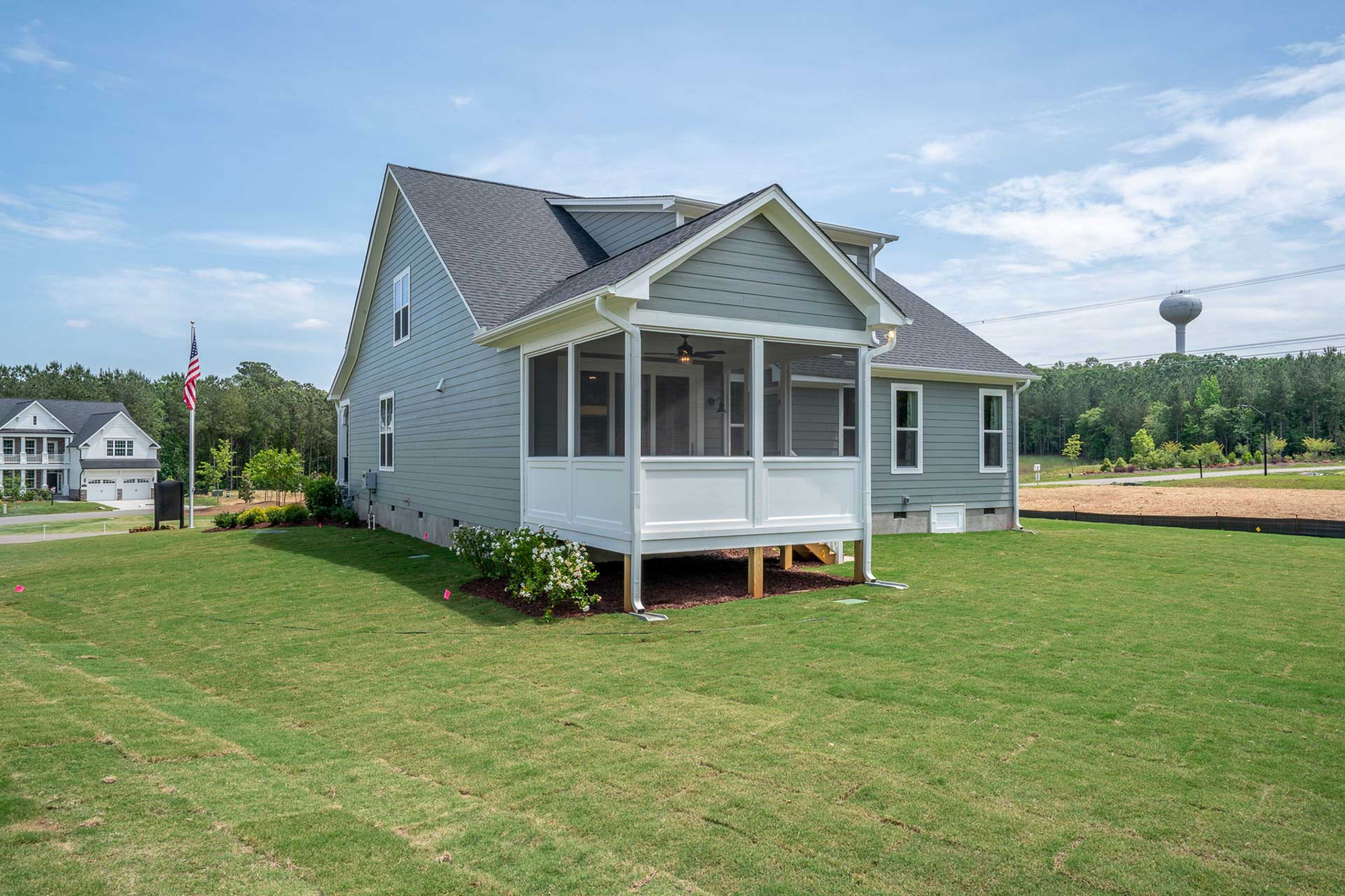 Gray-sided home with screened porch and American flag at Hasentree in Wake Forest, North Carolina by Davidson Homes