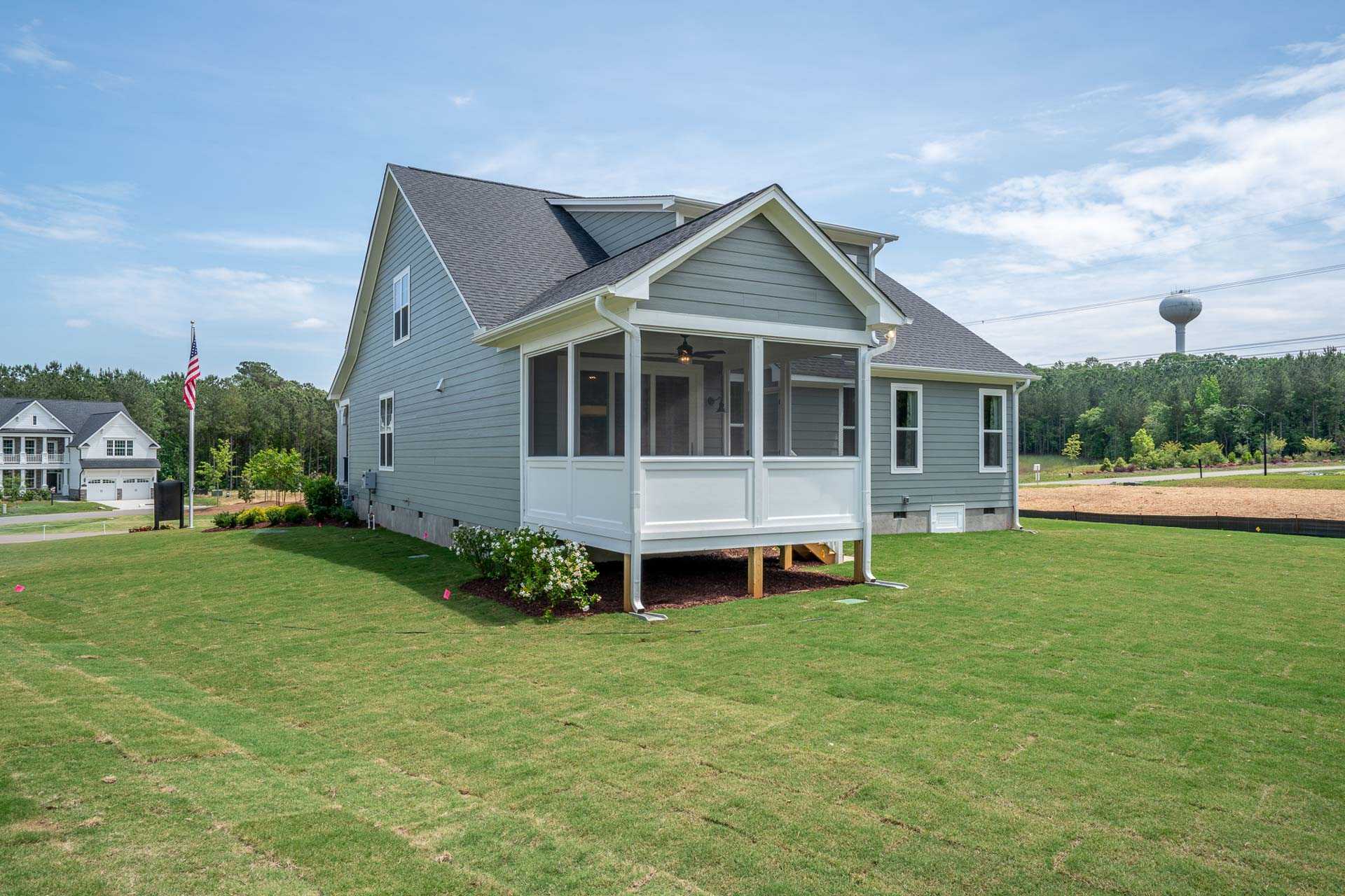 Gray-sided home with screened porch and American flag at Hasentree in Wake Forest, North Carolina by Davidson Homes