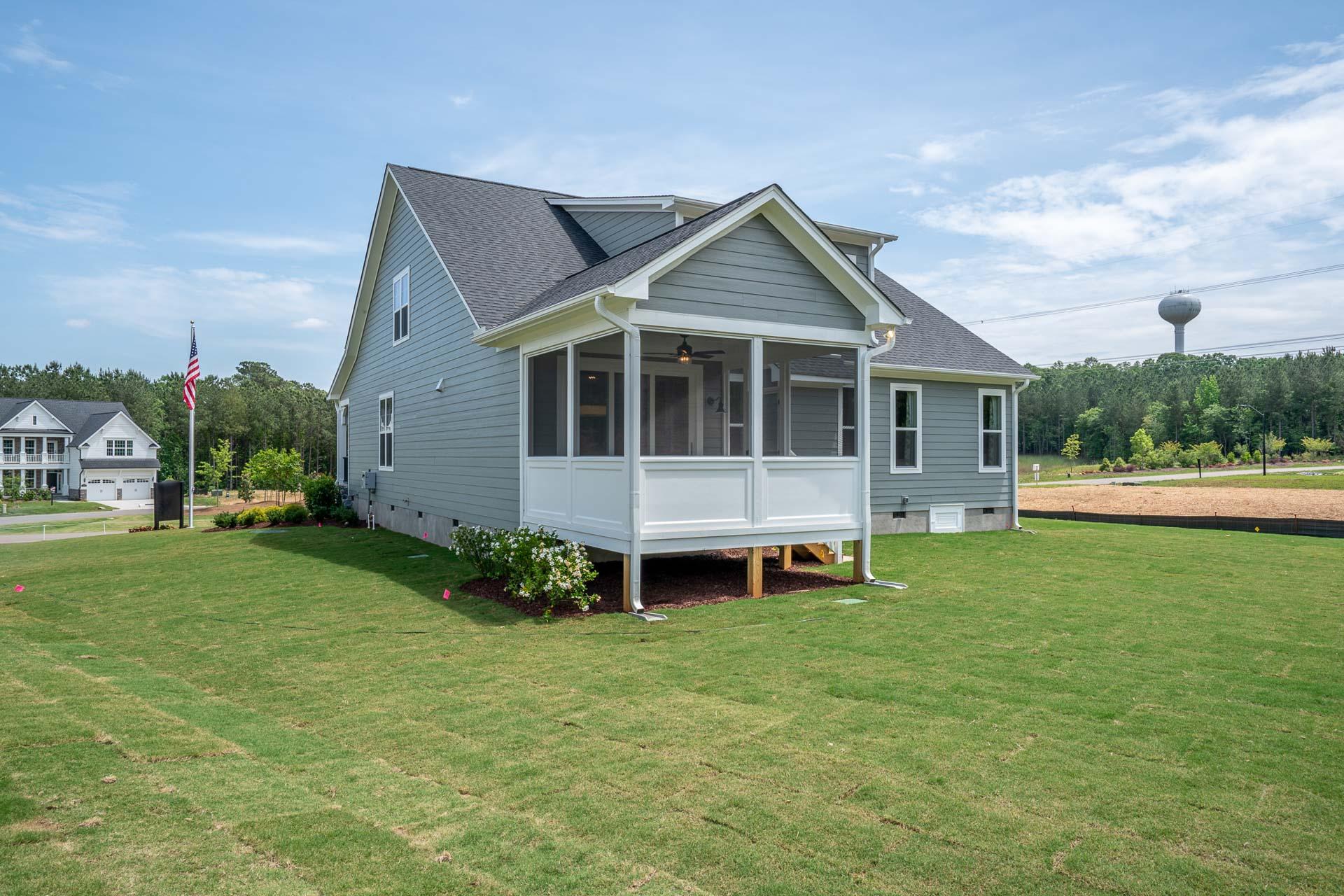 Gray-sided home with screened porch and American flag at Hasentree in Wake Forest, North Carolina by Davidson Homes