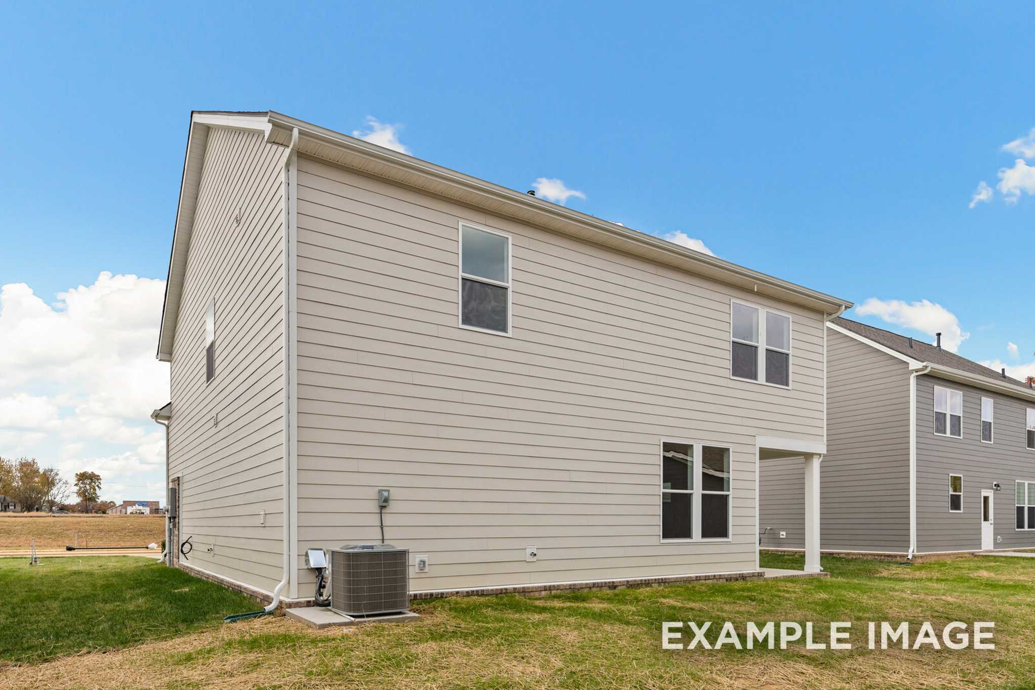 Side view of Murray A two-story home with beige siding, large windows, covered entry, and AC unit on lush lawn
