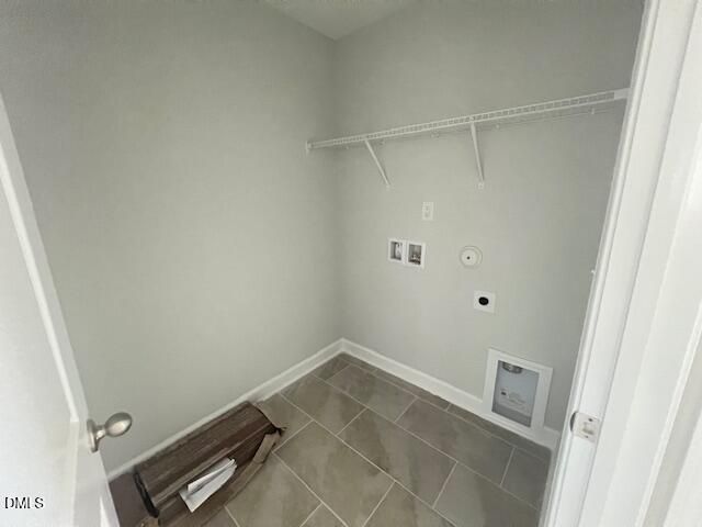 Spacious laundry room with gray walls, wooden shelving, washer-dryer hookups in The Adalynn A by Davidson Homes, Lillington NC