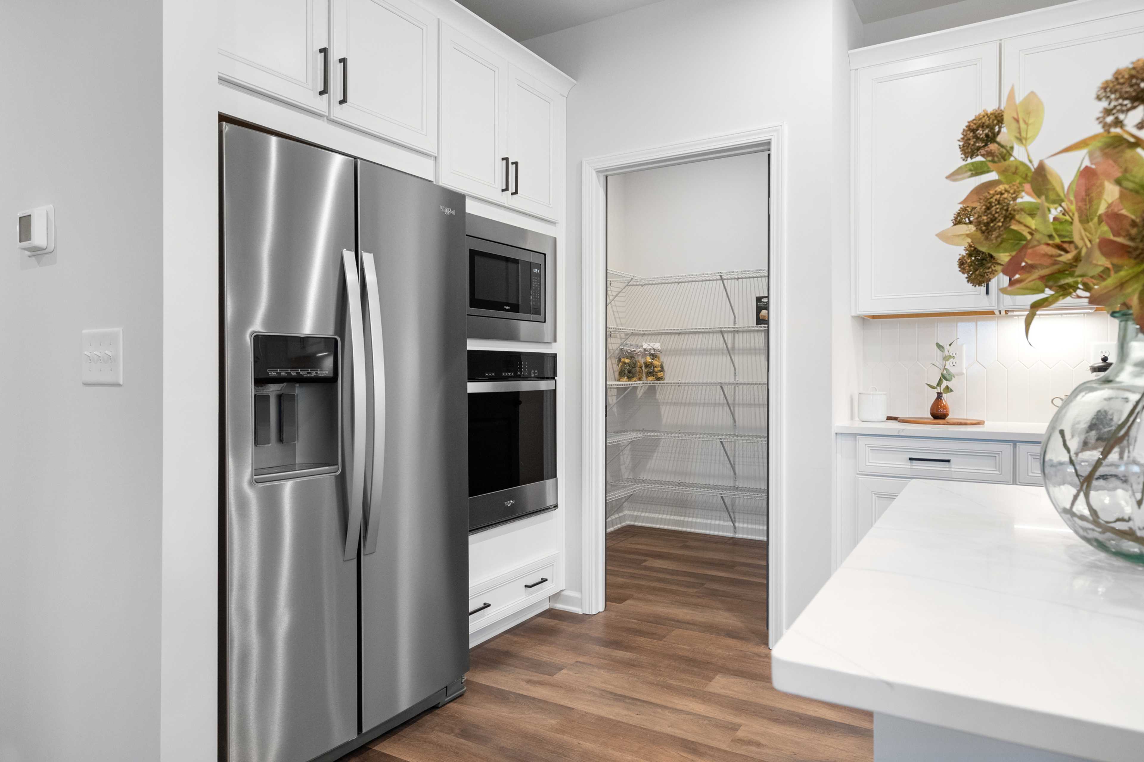 Modern kitchen at Kelly Preserve in Loganville GA by Davidson Homes with white cabinets, stainless steel appliances, and walk-in pantry