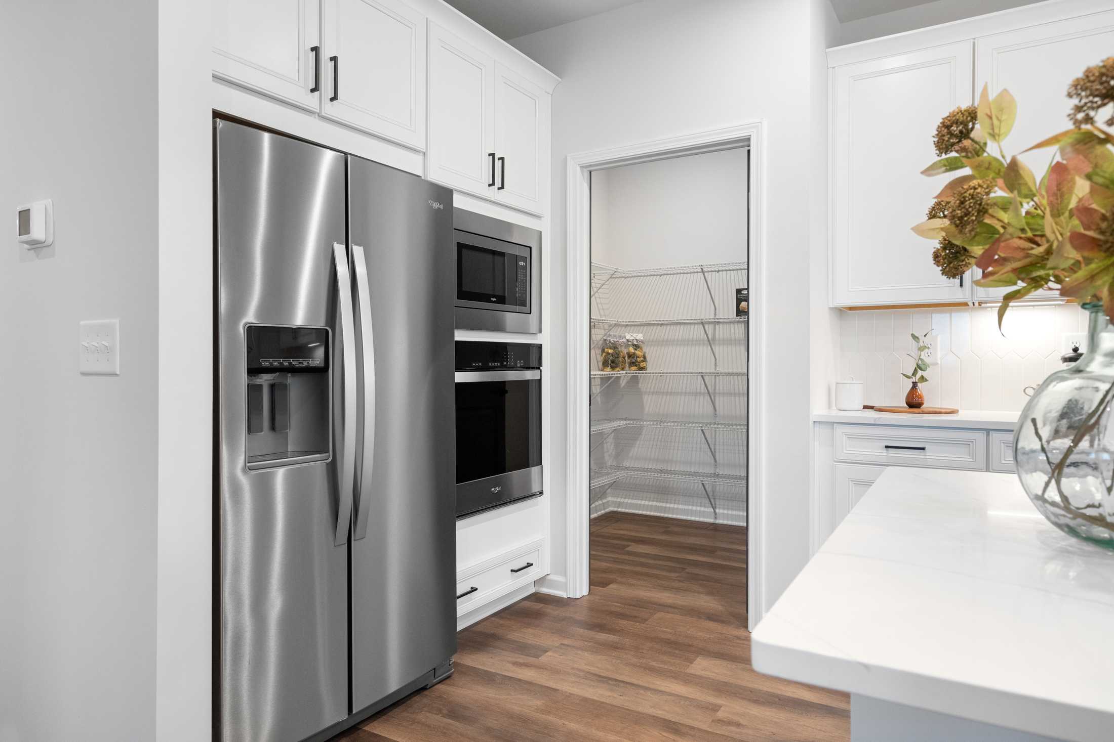 Modern kitchen at Kelly Preserve in Loganville GA by Davidson Homes with white cabinets, stainless steel appliances, and walk-in pantry