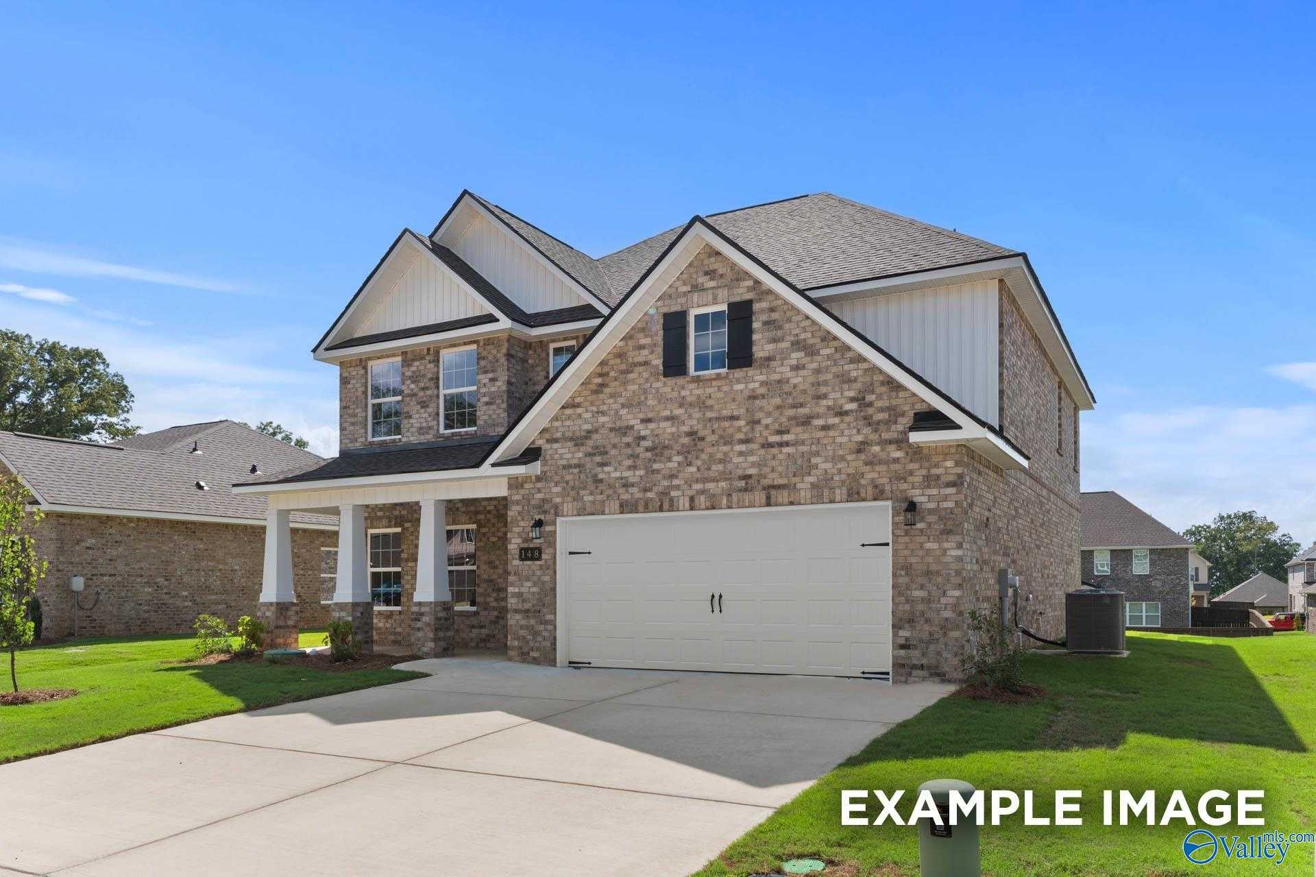 Two-story brick home with gabled roof, two-car garage, and columned front porch in Creekside, Harvest, Alabama