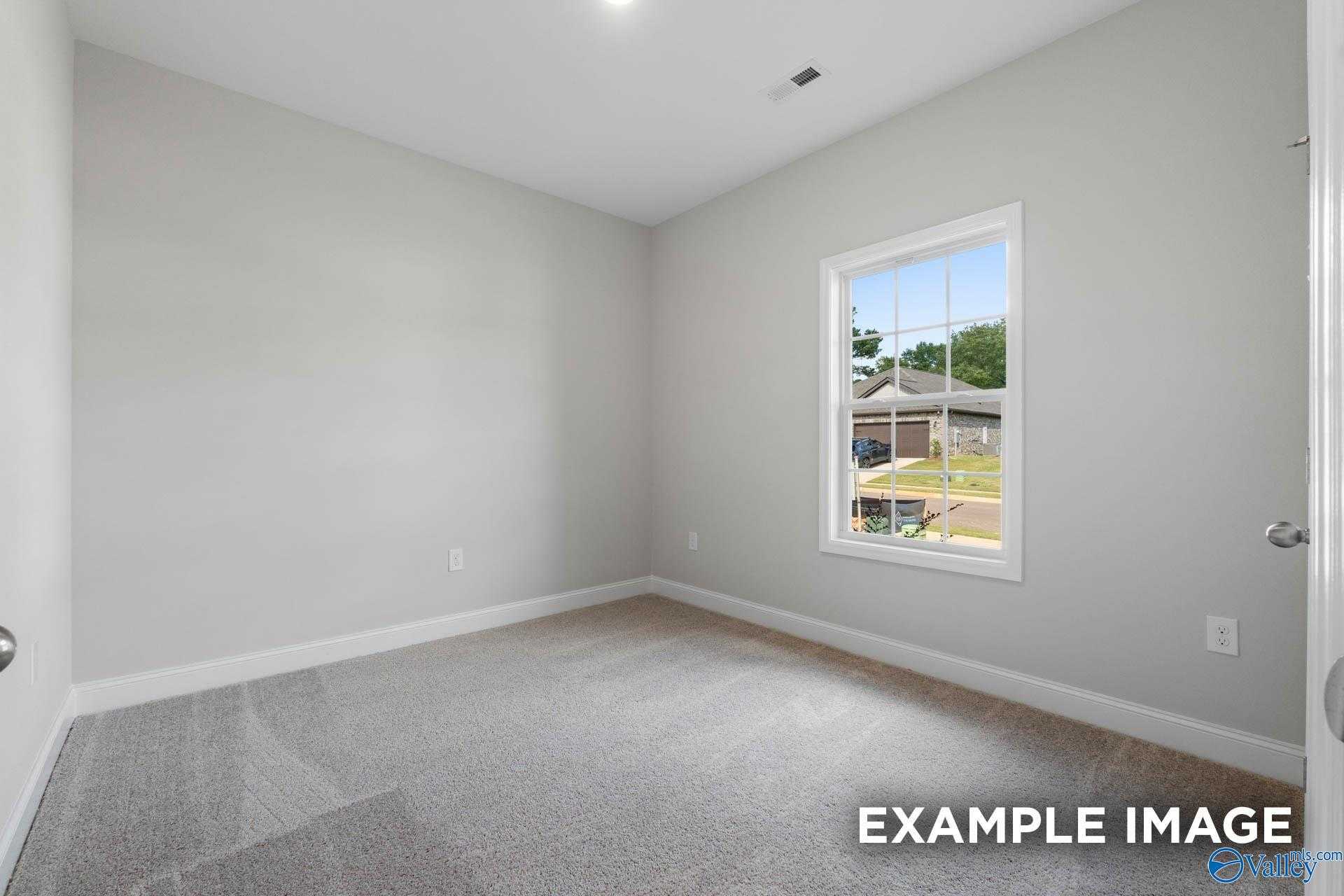 Bright secondary bedroom with gray walls, carpet flooring, and neighborhood view window in Davidson Homes The Butler, Huntsville, Alabama