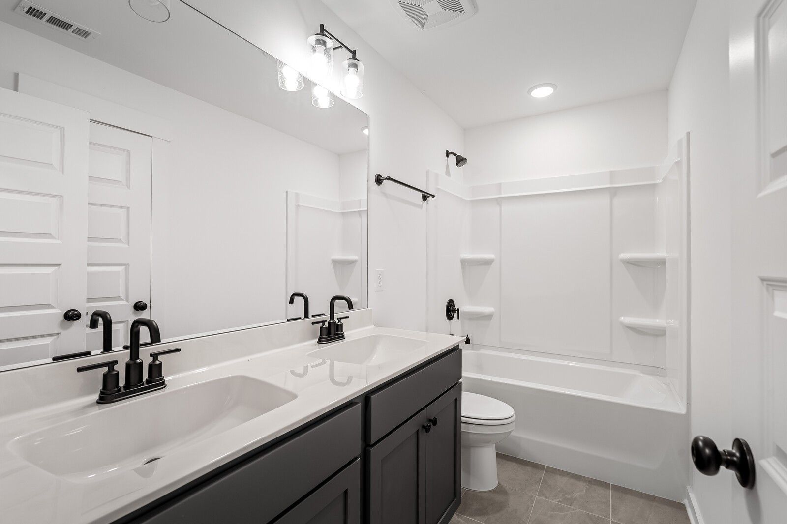Modern bathroom with double vanity, gray cabinets, bathtub, and walk-in shower in Davidson Homes The Ridgeport, Gallatin, TN
