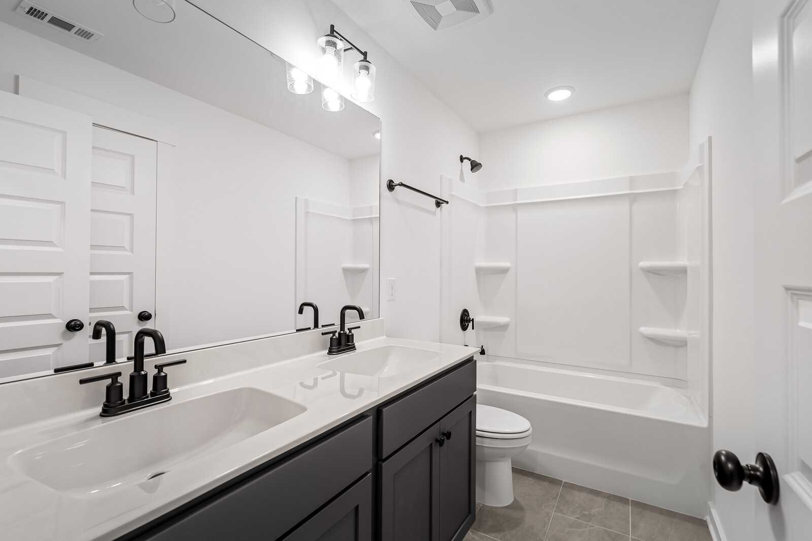 Modern bathroom with double vanity, gray cabinets, bathtub, and walk-in shower in Davidson Homes The Ridgeport, Gallatin, TN