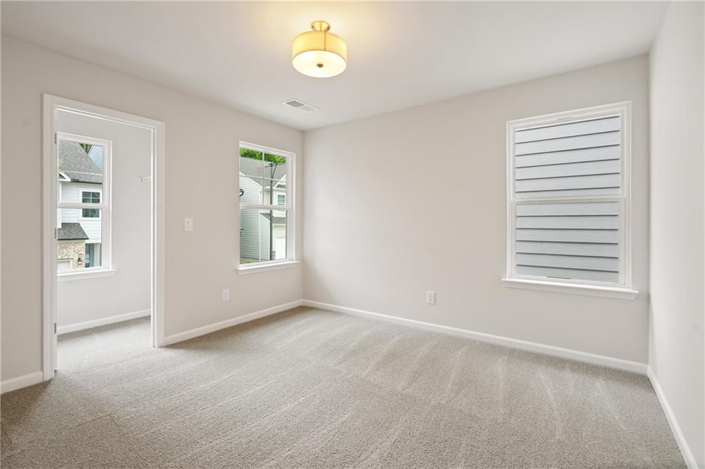 Bright secondary bedroom with neutral beige walls, carpet flooring, and window blinds in Davidson Homes The Cary B, Kennesaw, GA
