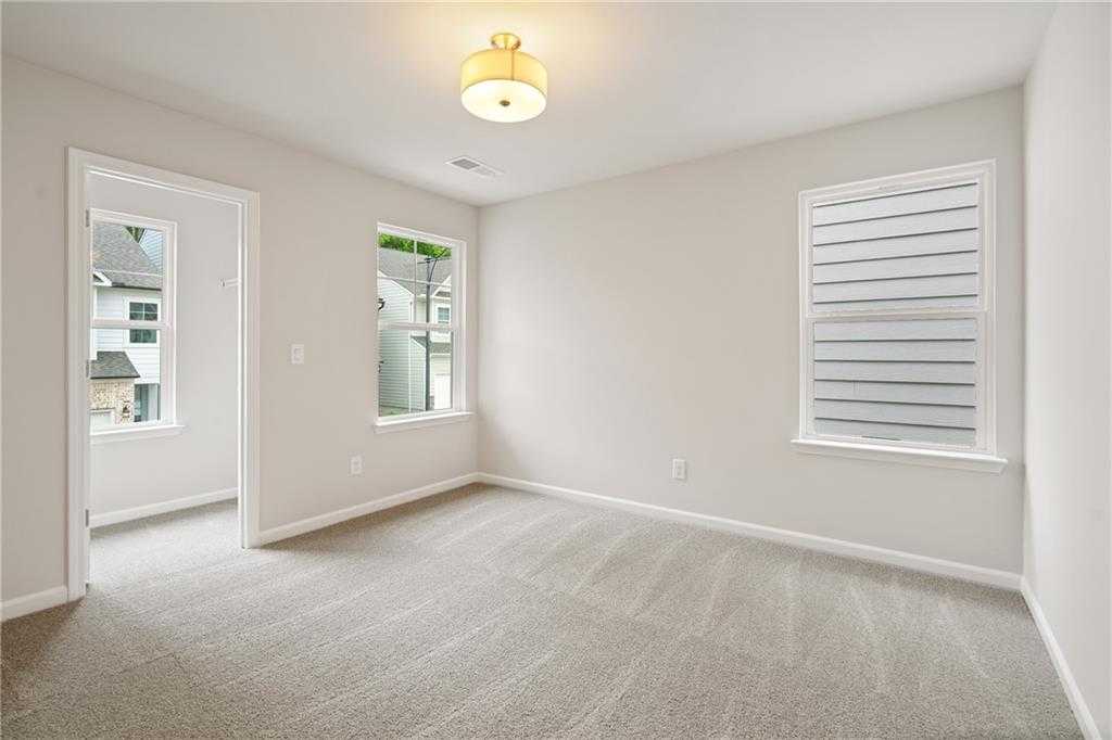 Bright secondary bedroom with neutral beige walls, carpet flooring, and window blinds in Davidson Homes The Cary B, Kennesaw, GA