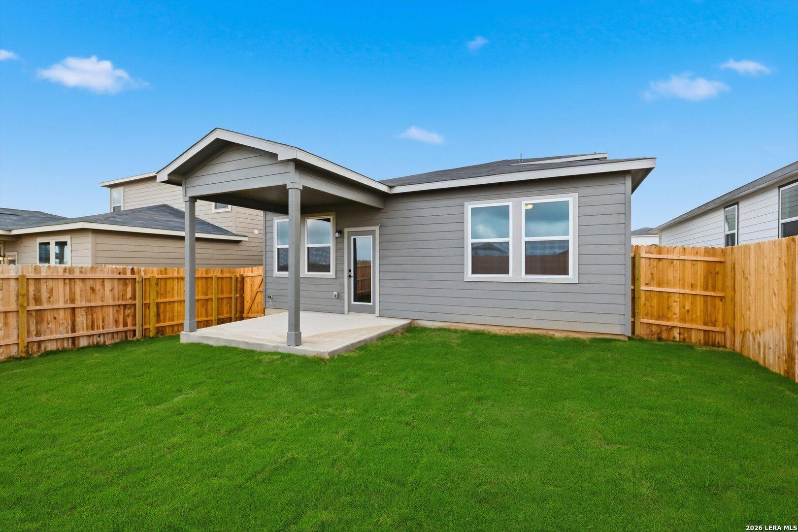 Covered back patio with columns overlooking lush green fenced yard in Davidson Homes The Blanco C, Agave, San Antonio