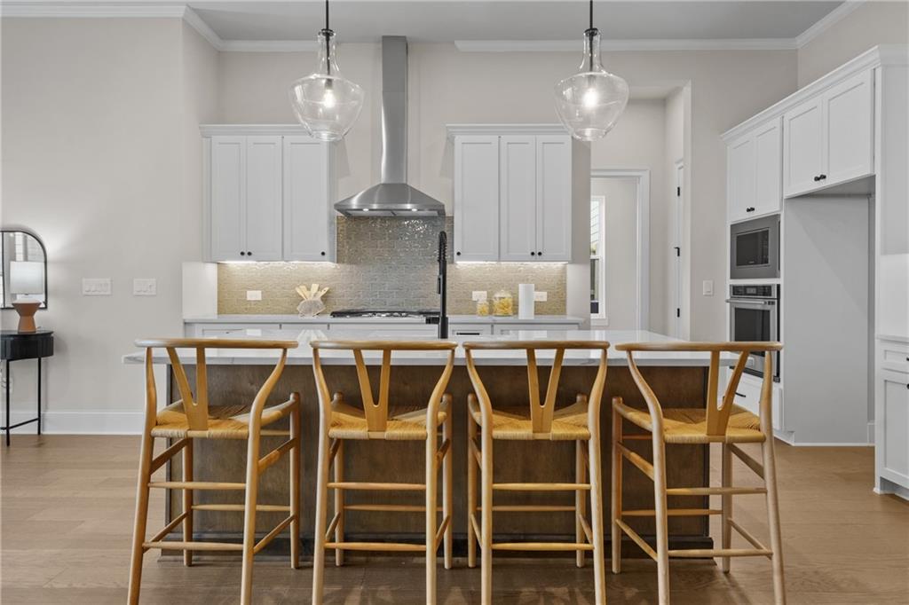 Modern kitchen with white shaker cabinets, stainless appliances, and wood island bar stools in Davidson Homes Seaside B, Woodstock, GA