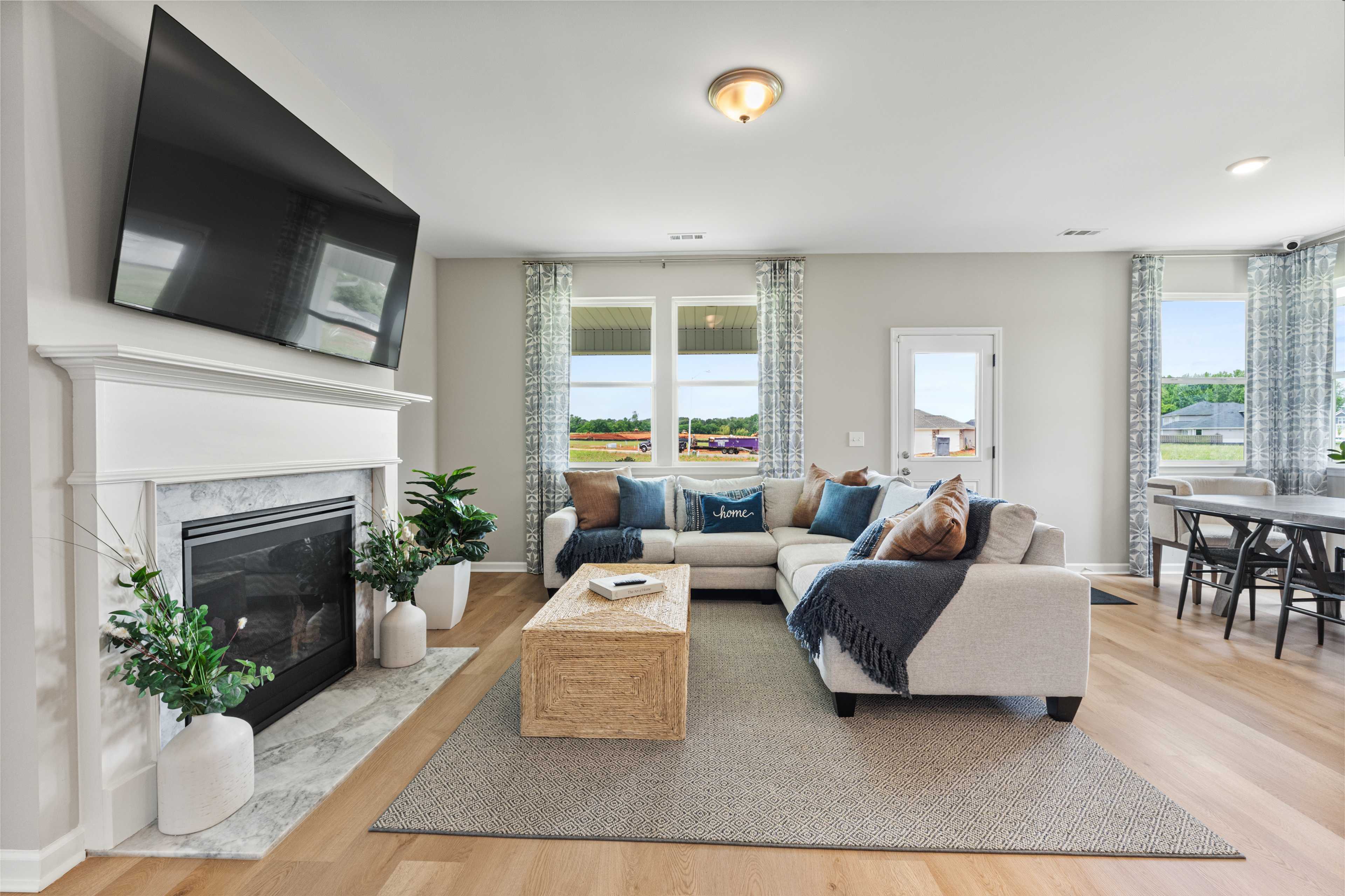 Spacious living room at Forest Glen in Hazel Green Alabama with stone gas fireplace, sectional sofa, hardwood floors, and wall-mounted TV