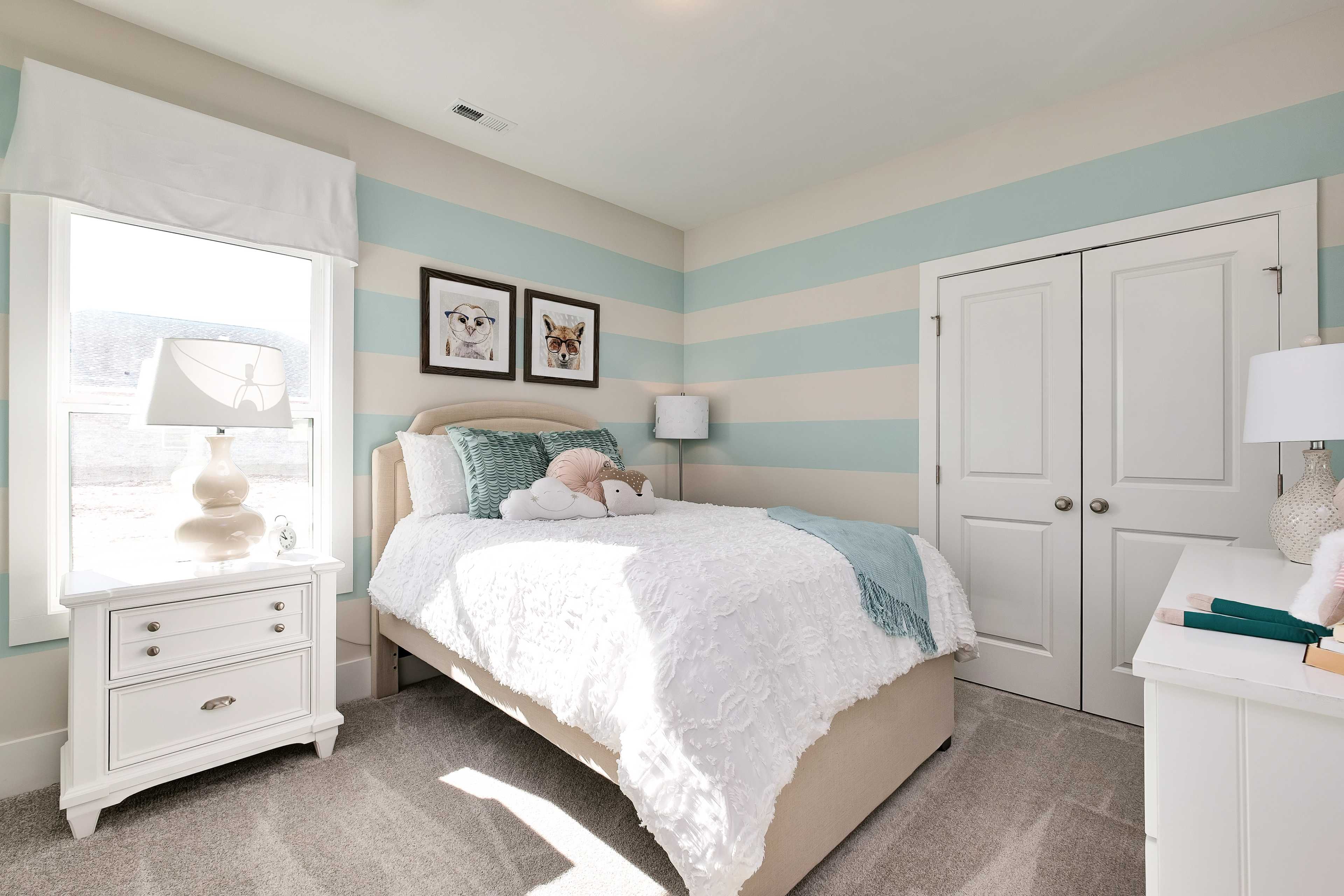 Charming girl's bedroom at Mallard Landing in Athens Alabama with light blue striped walls, twin bed, and dog artwork