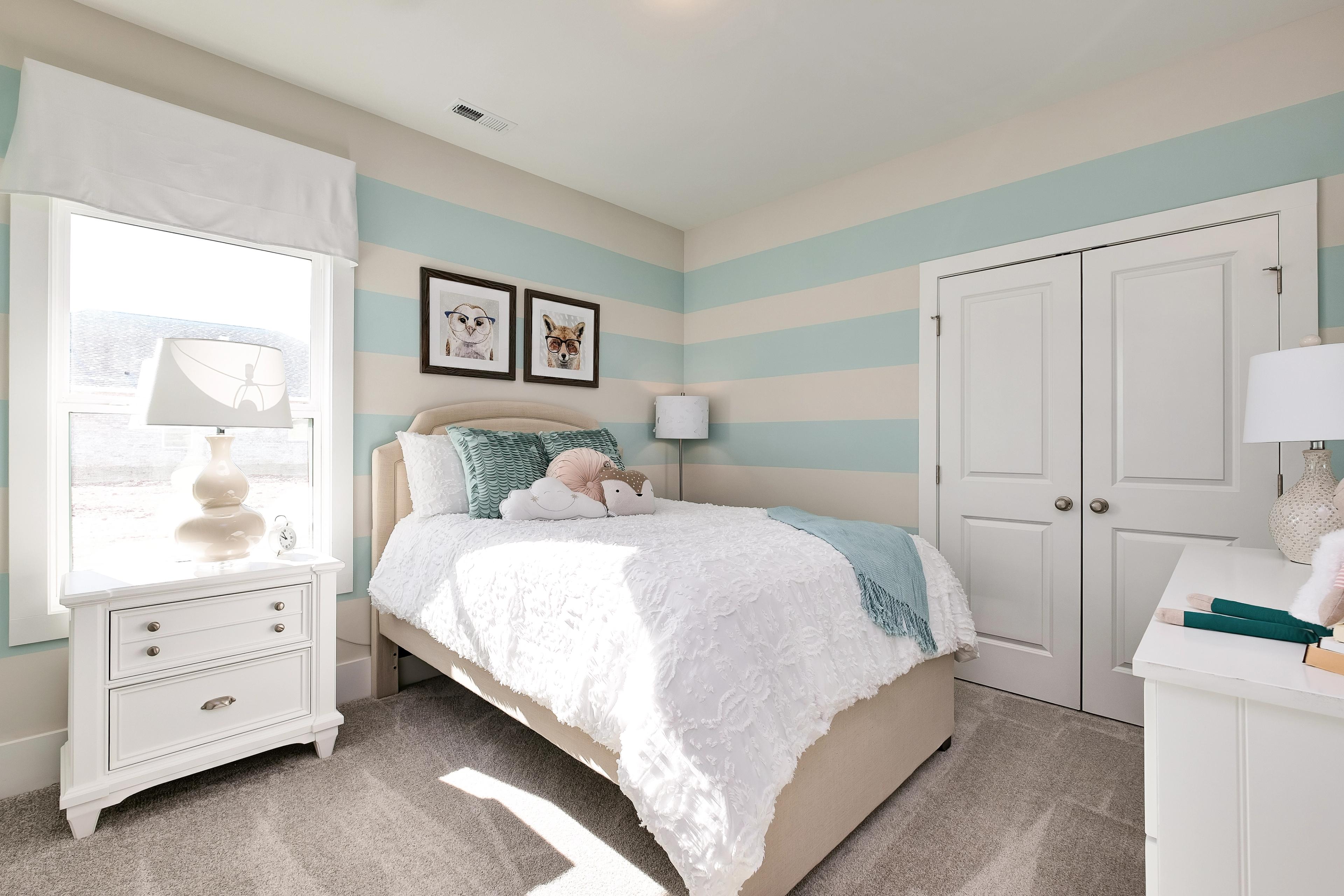 Charming girl's bedroom at Mallard Landing in Athens Alabama with light blue striped walls, twin bed, and dog artwork