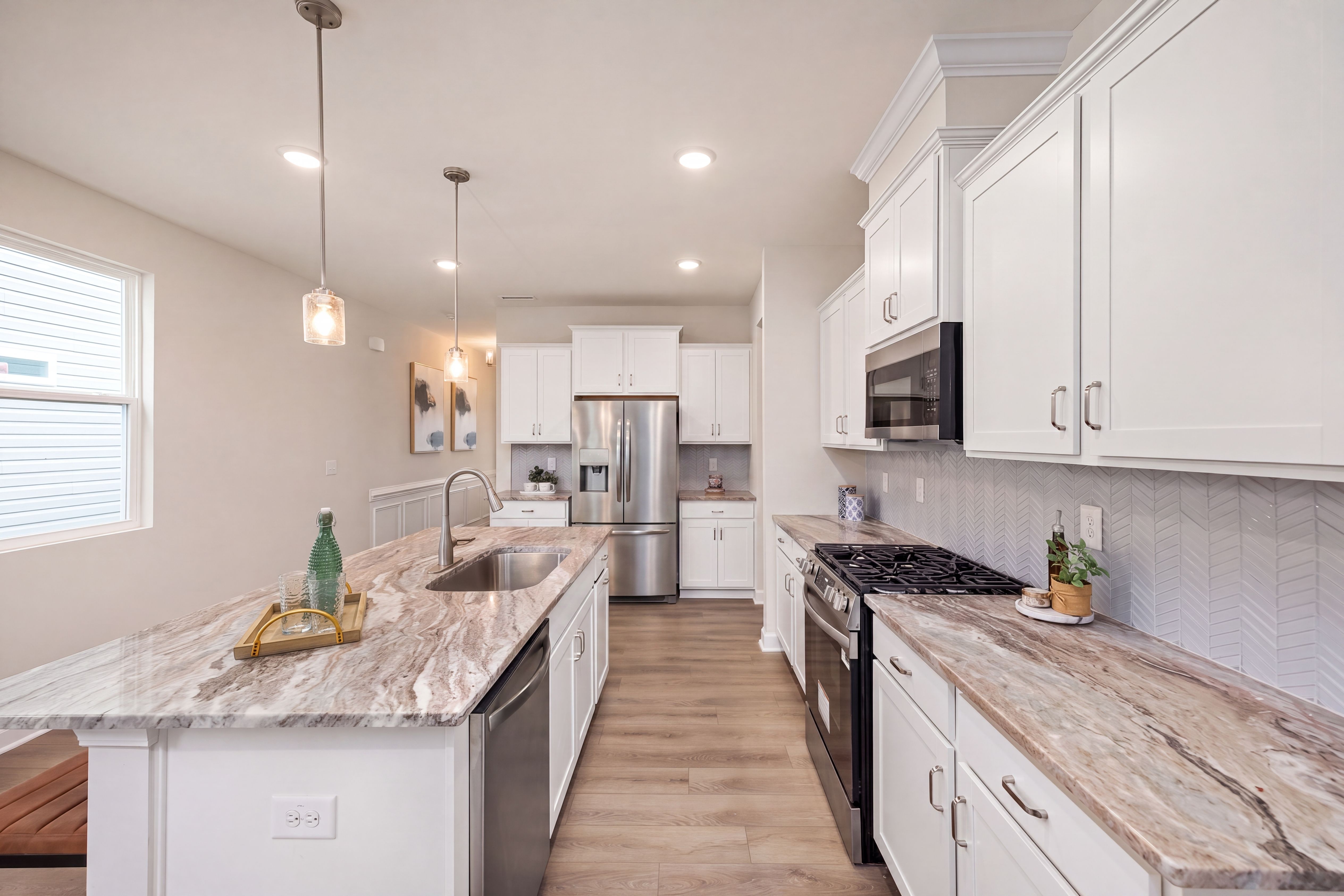 Modern kitchen at Gregory Village in Lillington, NC by Davidson Homes featuring white cabinets and stone countertops.