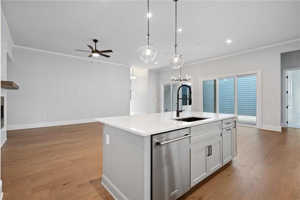 Open-concept kitchen with quartz island, stainless appliances, pendant lights, and hardwood floors in Davidson Homes The Seaside B, Woodstock, Georgia