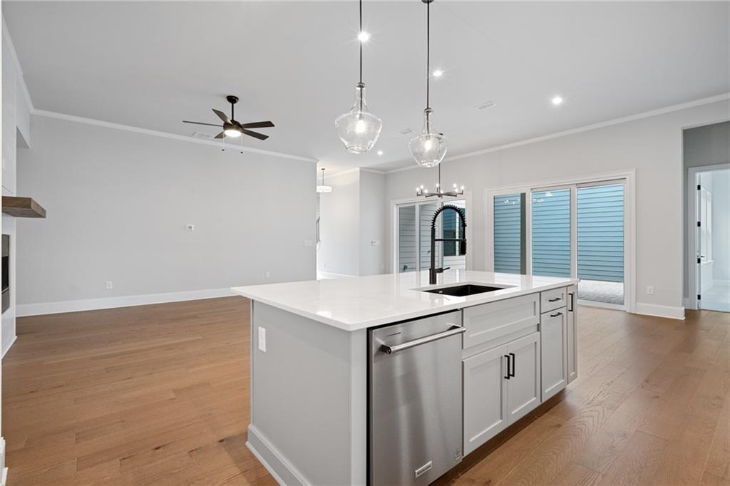 Open-concept kitchen with quartz island, stainless appliances, pendant lights, and hardwood floors in Davidson Homes The Seaside B, Woodstock, Georgia