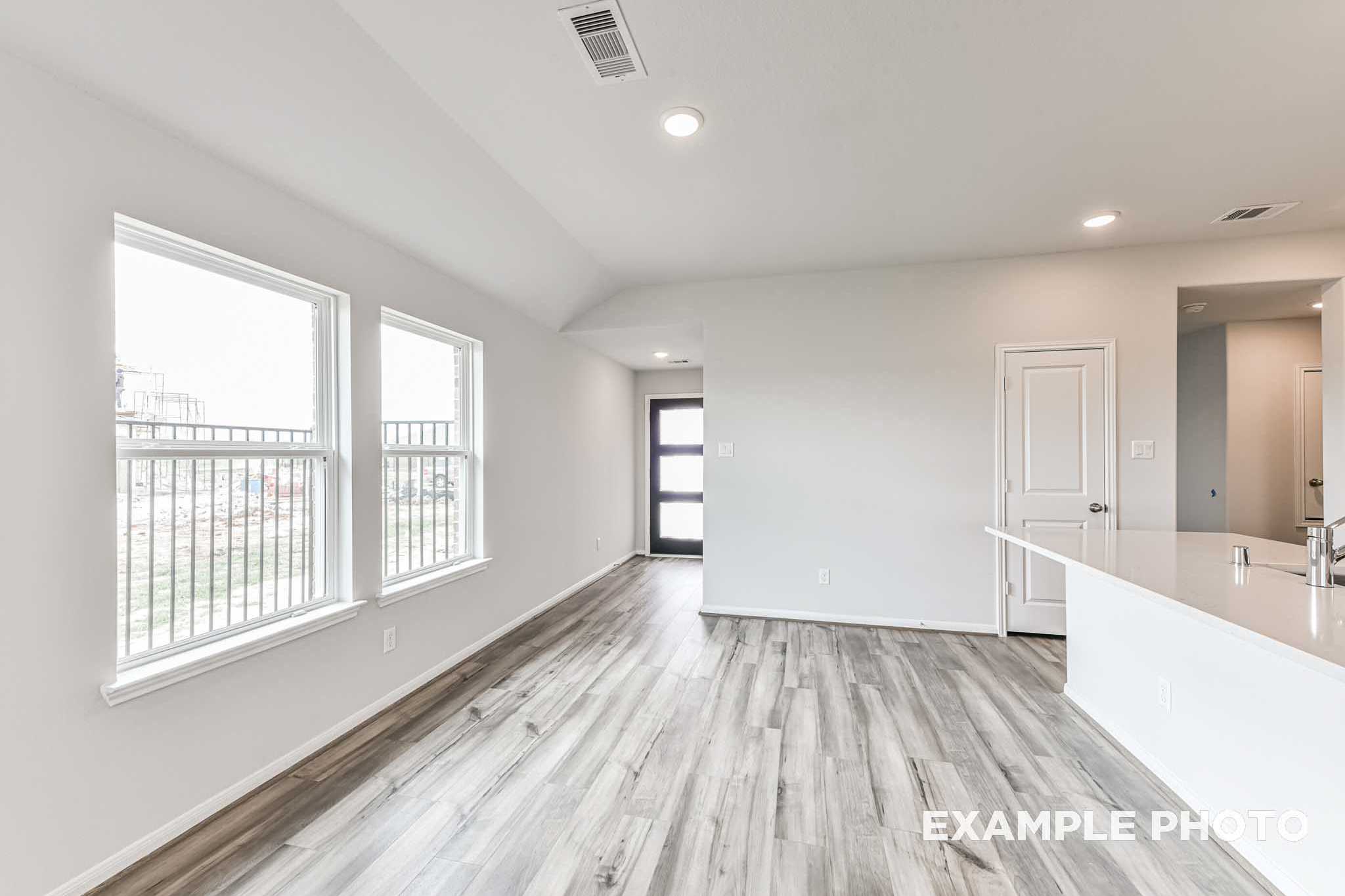 Spacious open-concept living area in The Costa C with gray hardwood floors, large windows, and white kitchen island