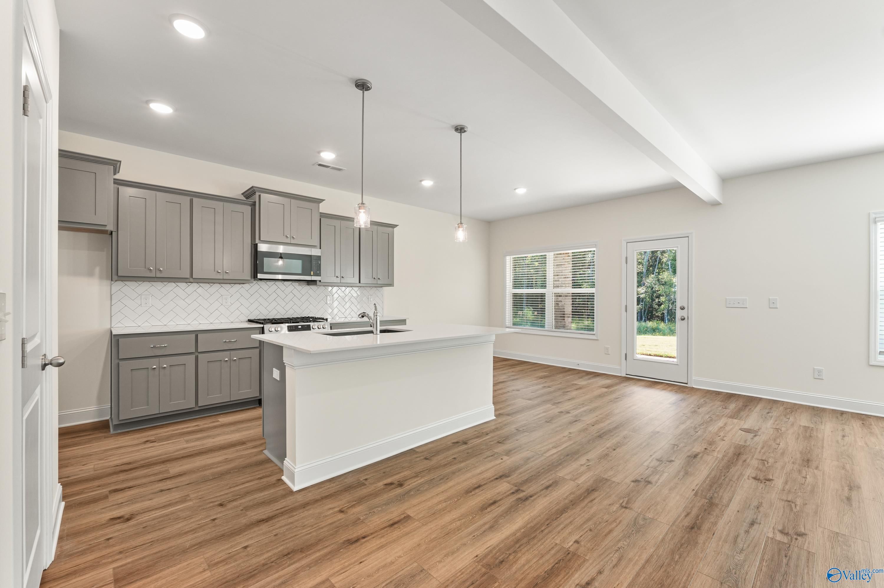 Modern open-concept kitchen with gray shaker cabinets, white quartz island, subway tile backsplash in Davidson Homes The Shelby A, Athens AL