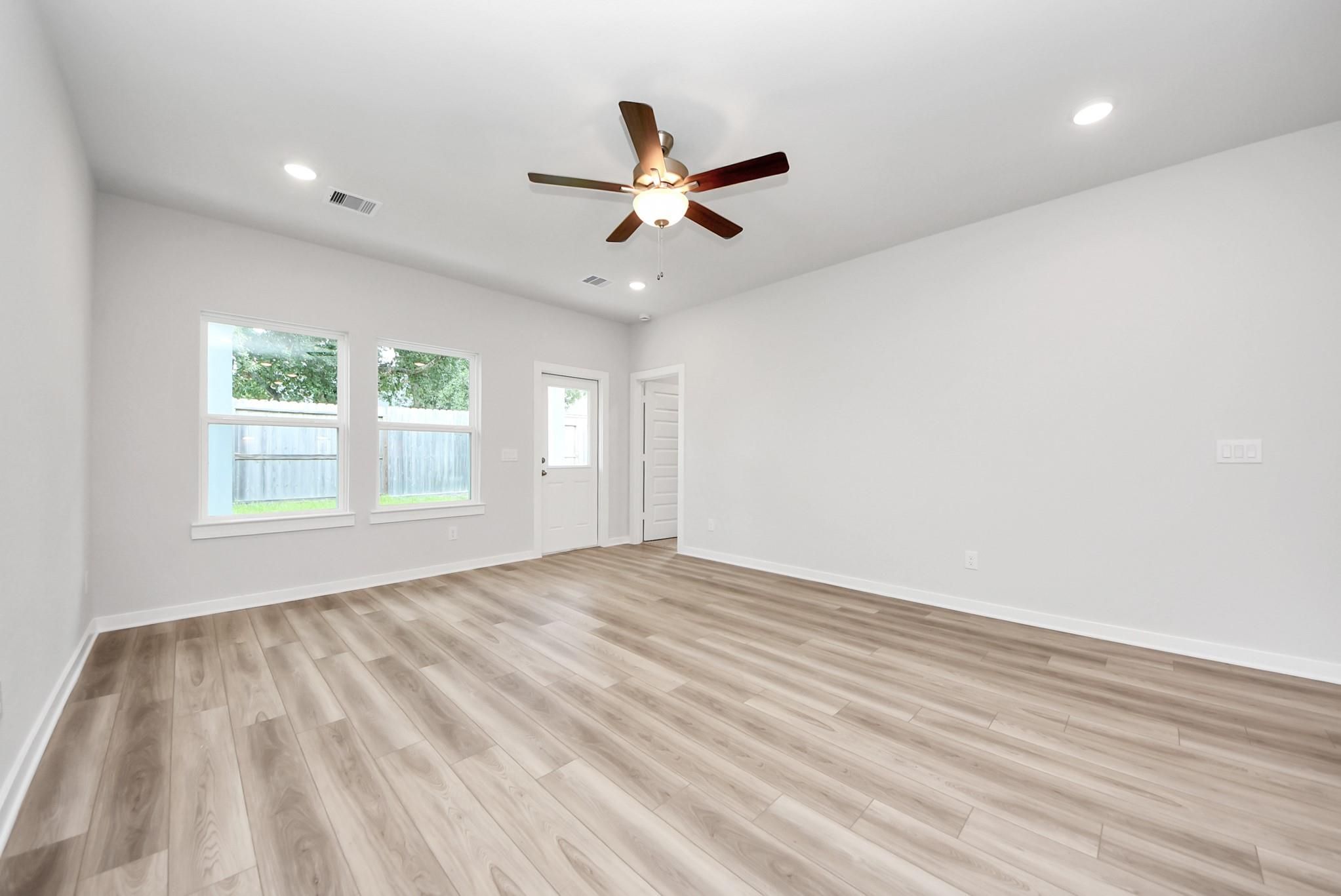 Spacious living room with light wood-look flooring and ceiling fan in The Sabine E floor plan, Windmill Estates, Magnolia.