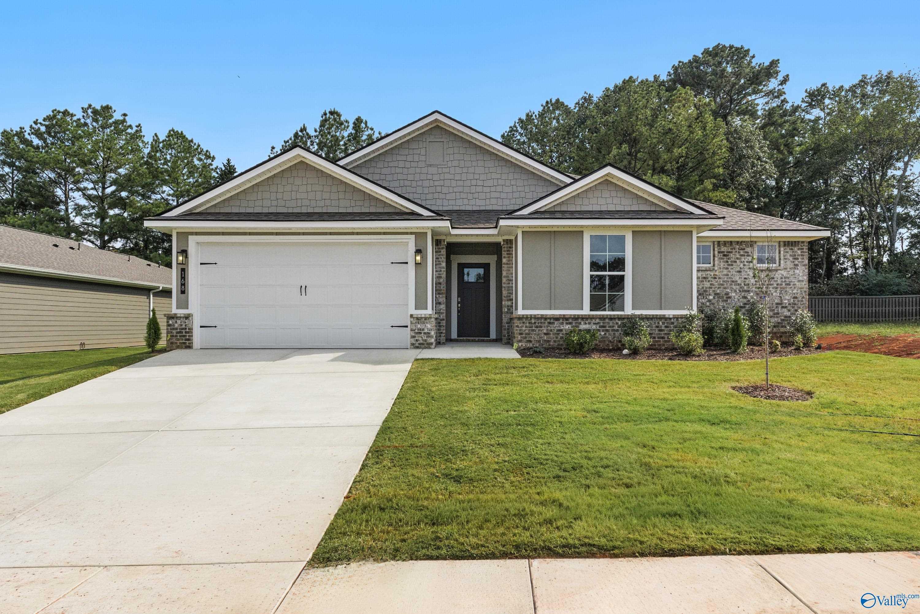 Modern single-story home with 2-car garage, gray shingle roof, stone accents, and lush lawn in Evergreen Mill, Madison, Alabama