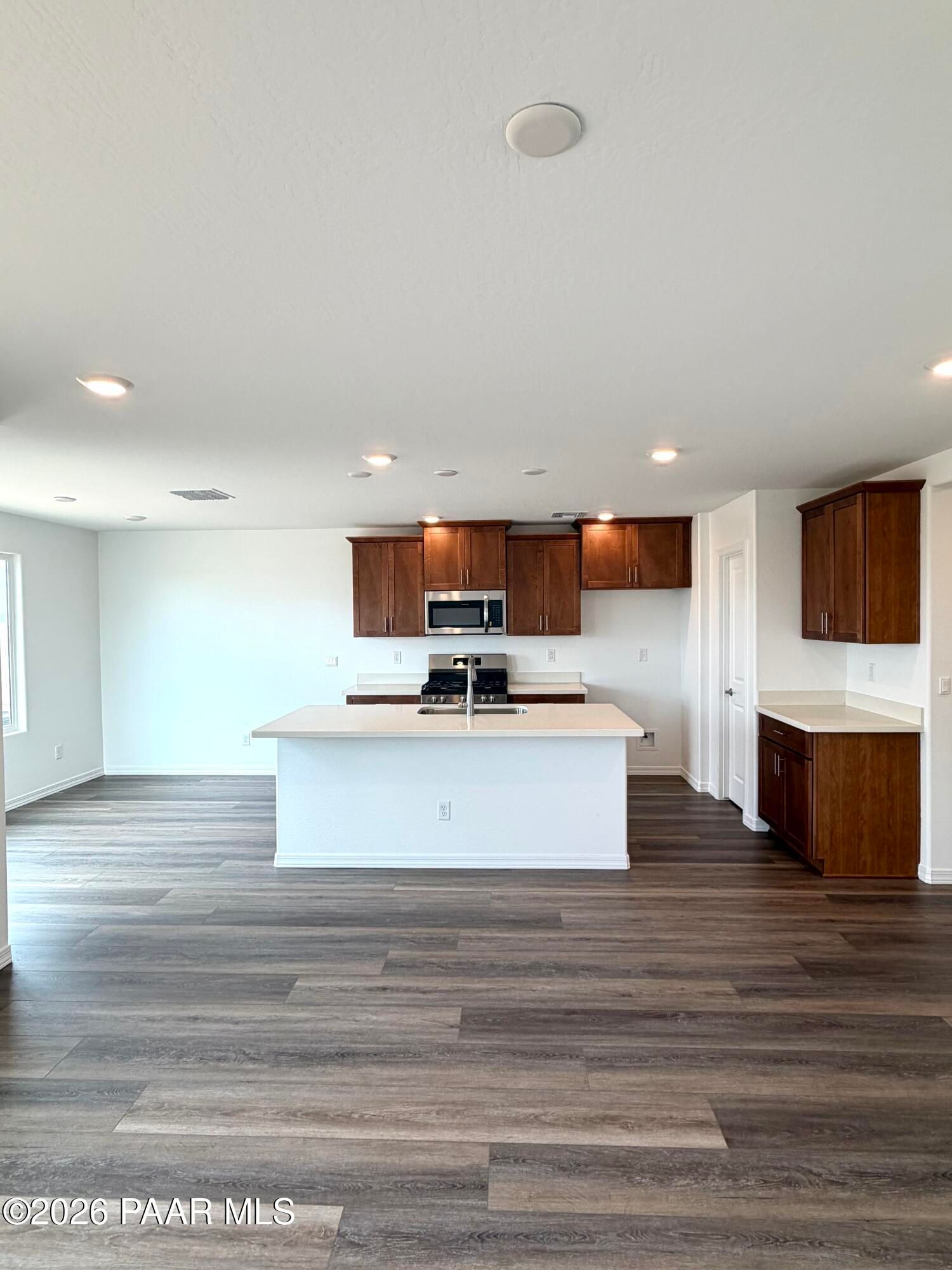 Open-concept kitchen with wood cabinets and center island in The Raleigh A floor plan at South Ranch, Prescott, Arizona.