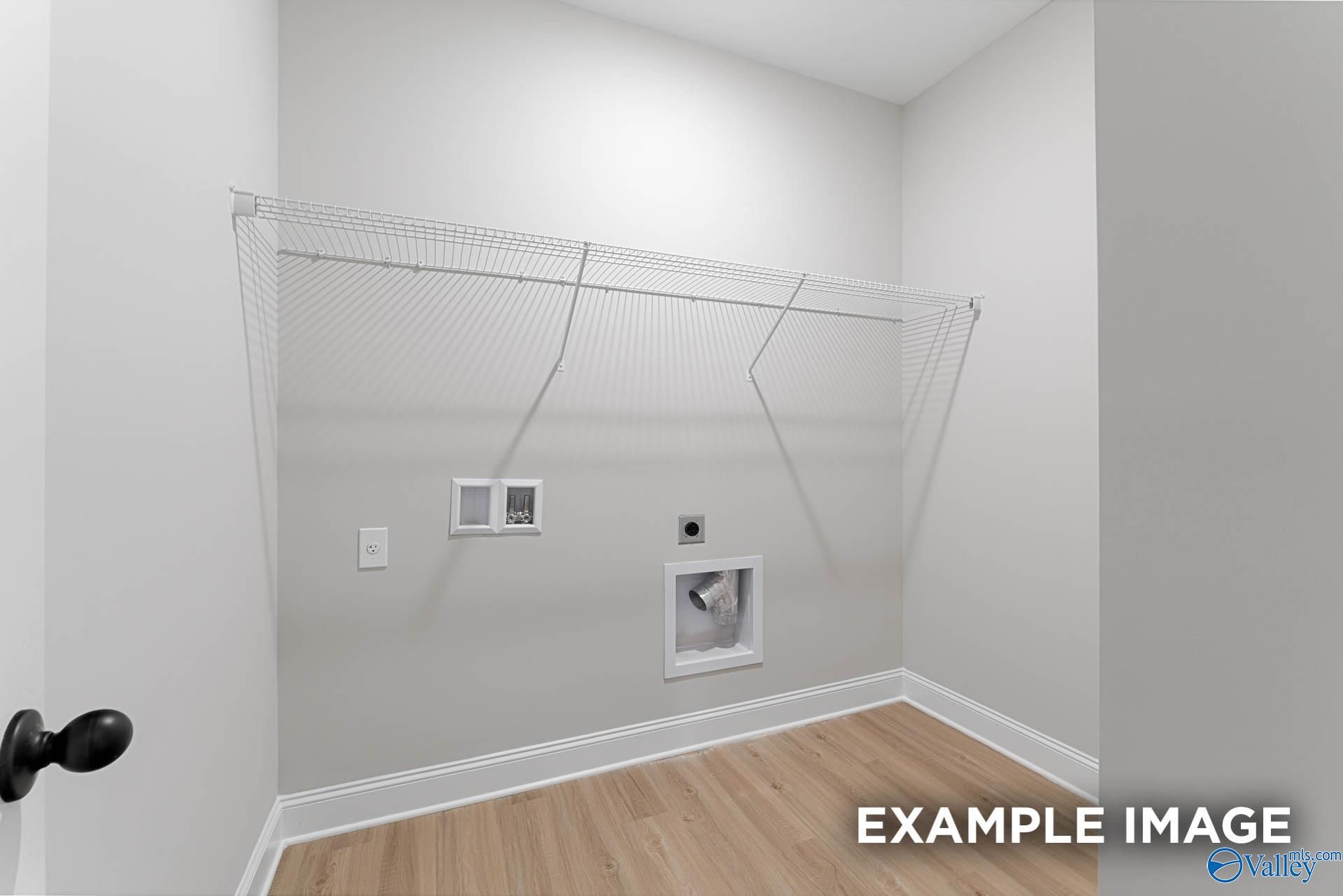 Bright laundry room with wire shelving, outlets, dryer vent, and hardwood floors in Davidson Homes The Daphne D, Meridianville, AL