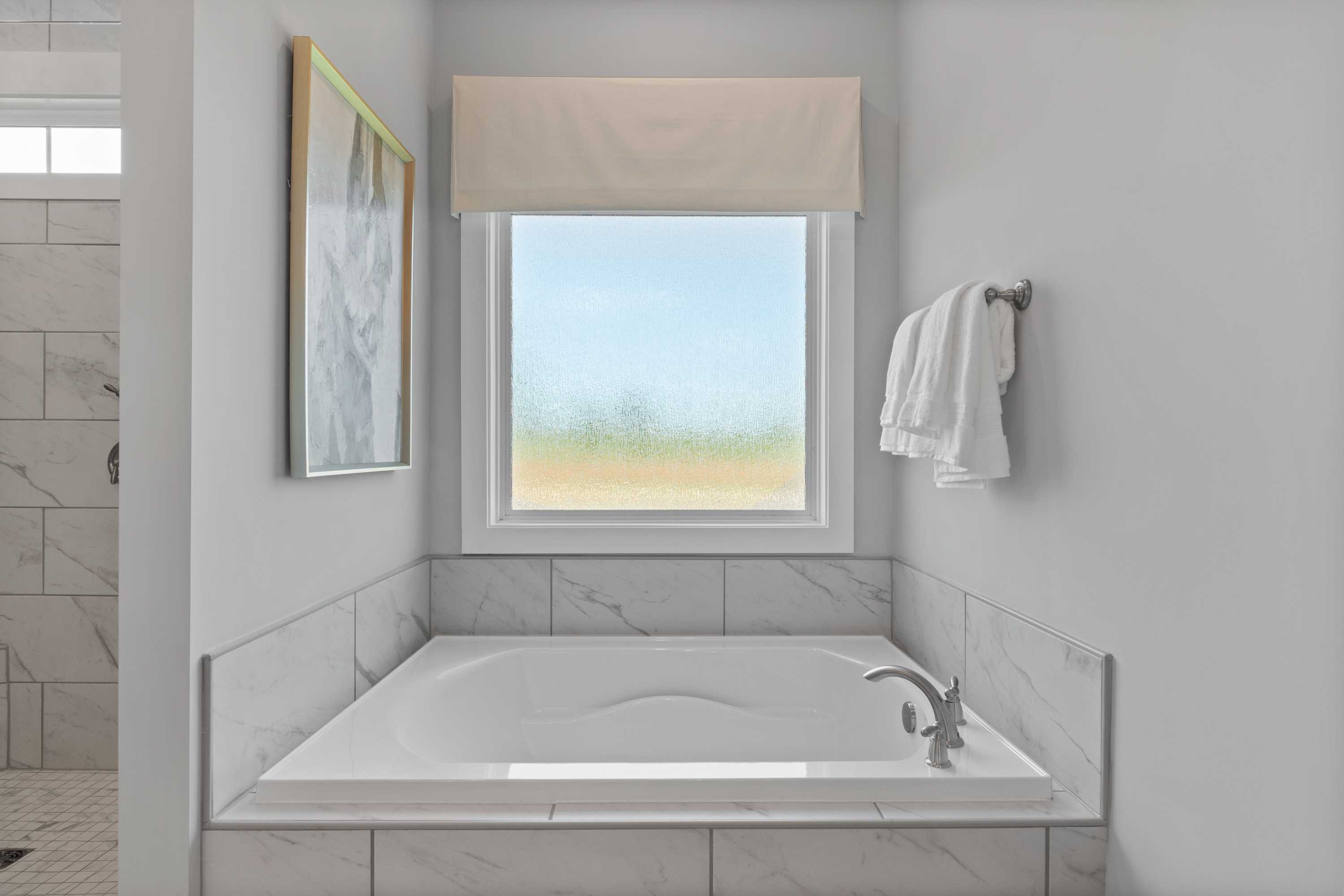 Luxurious master bathroom at Creekside in Harvest, Alabama with freestanding soaking tub, subway tile, and window view