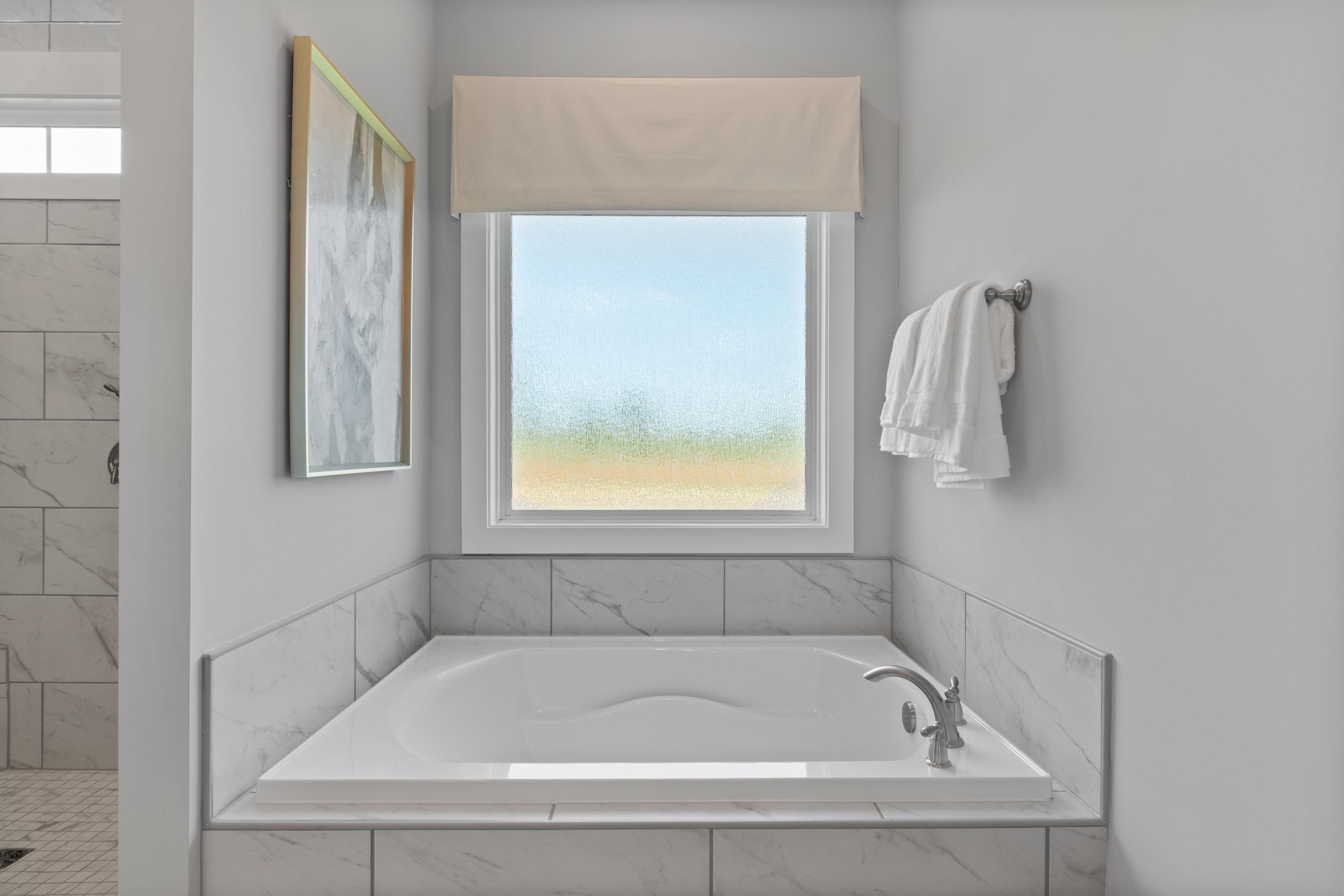 Luxurious master bathroom at Creekside in Harvest, Alabama with freestanding soaking tub, subway tile, and window view
