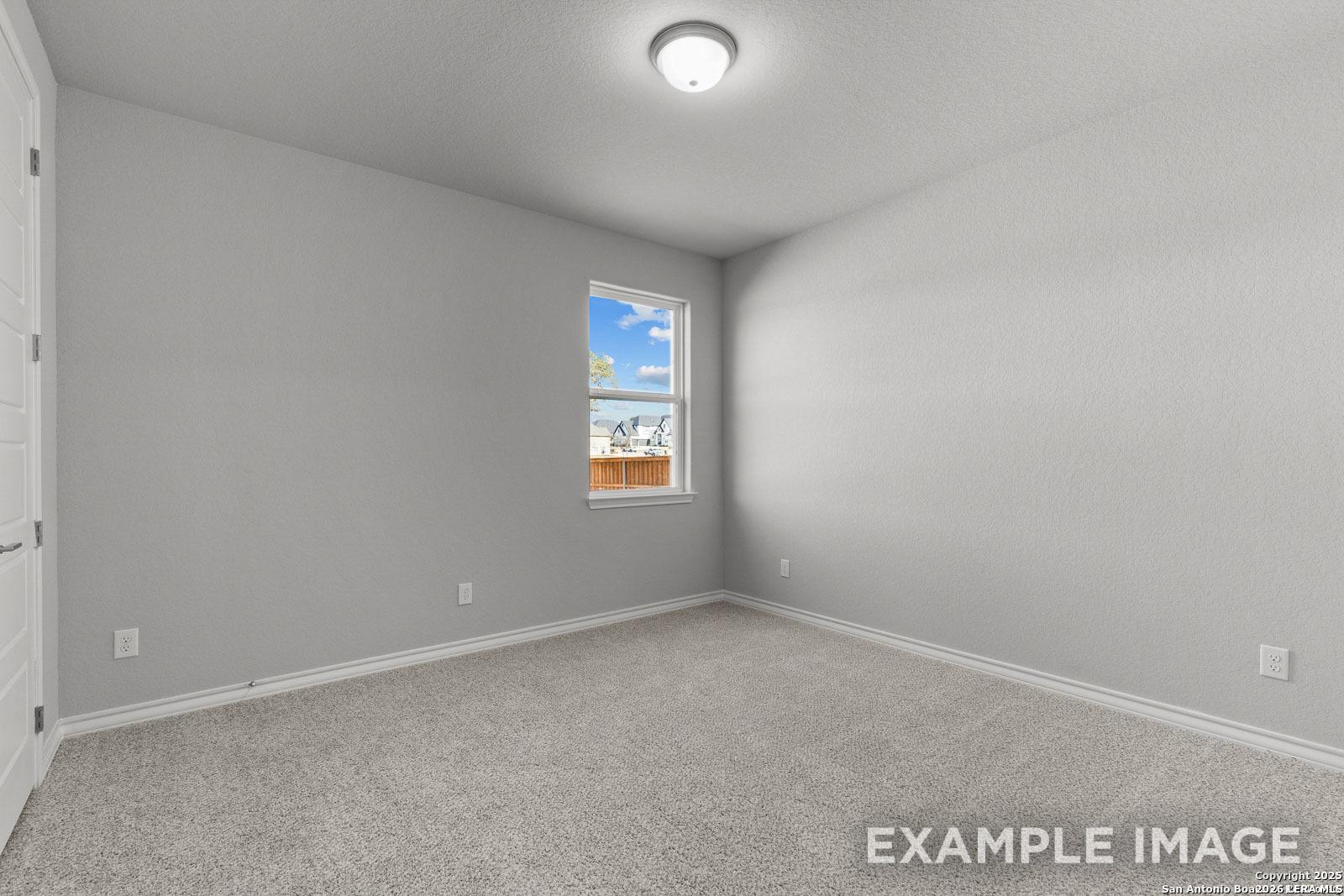 Bright secondary bedroom with neutral carpet and gray walls in The Oxford F floor plan at Potranco Oaks, Castroville.