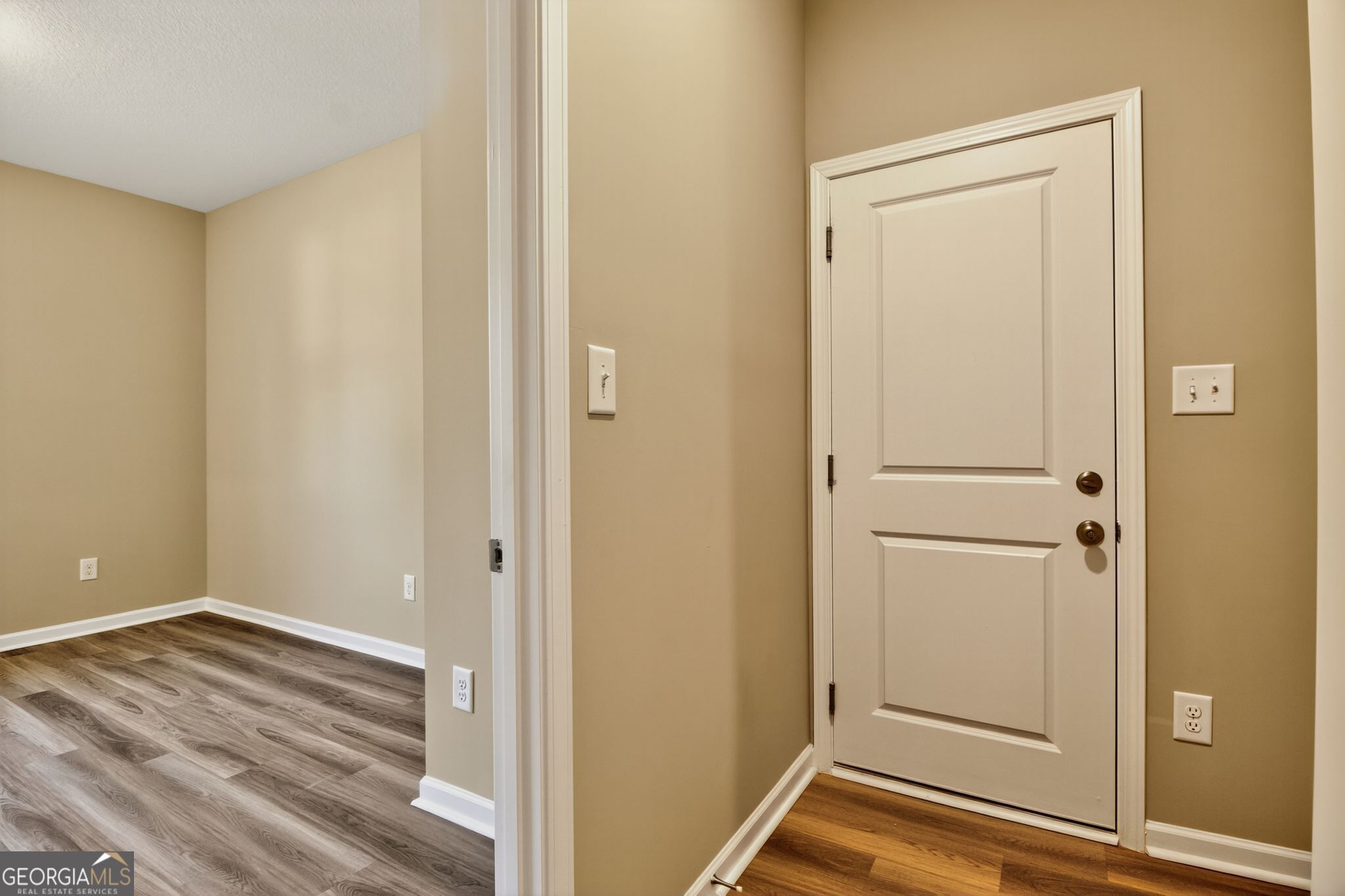Empty bedroom with neutral beige walls, luxury vinyl plank flooring, and white closet door in The Luna 4-bedroom home by Evermore Homes in Perry, Georgia