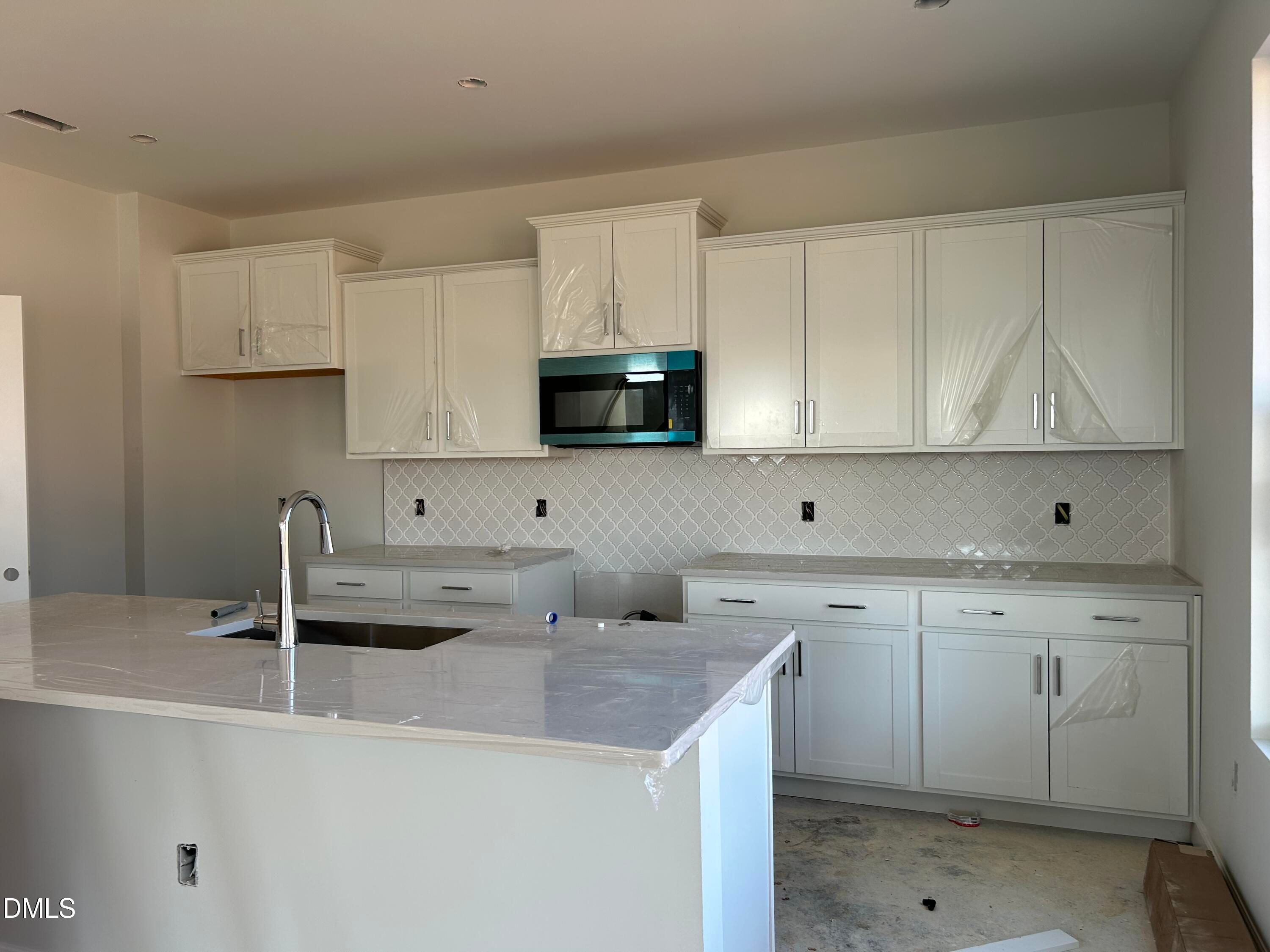 Modern white kitchen with quartz island, subway tile backsplash, and stainless hood in Davidson Homes The Chestnut B, Lillington, NC