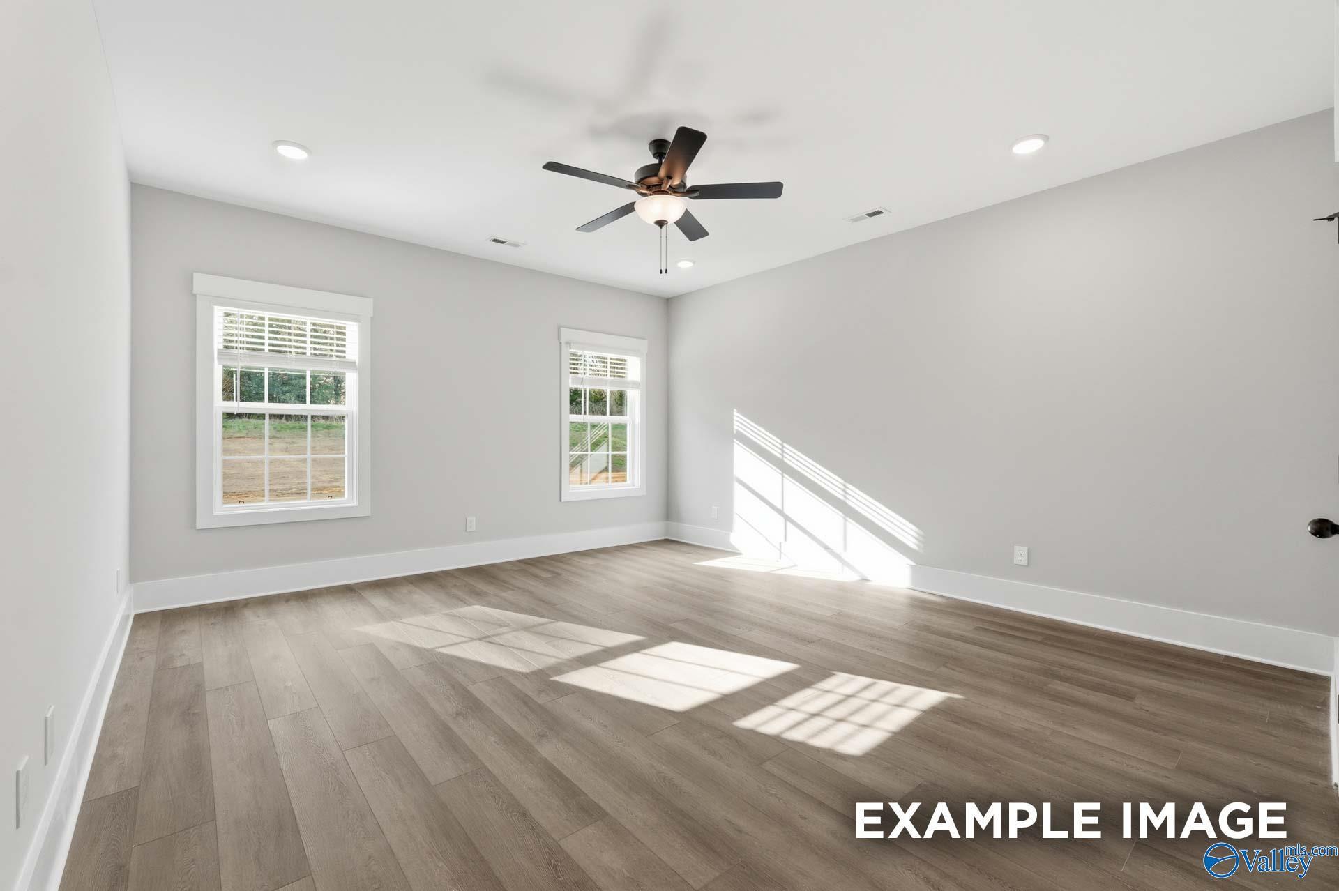 Spacious, light-filled bedroom with wood-style flooring in The Rockford floor plan by Davidson Homes in Briercreek.