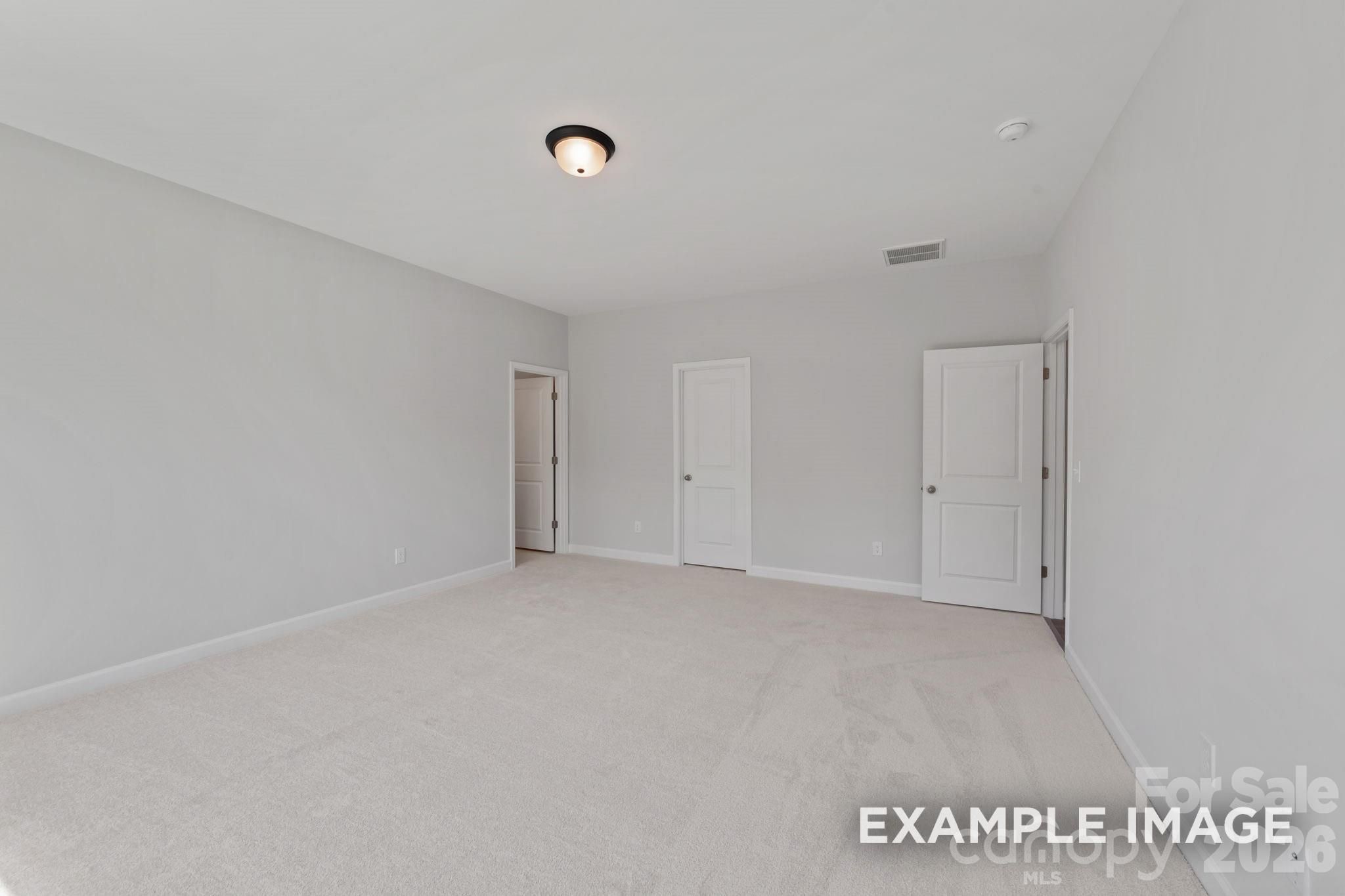 Spacious carpeted bedroom with neutral walls in The Magnolia B floor plan at Windgate in Mooresville, North Carolina.