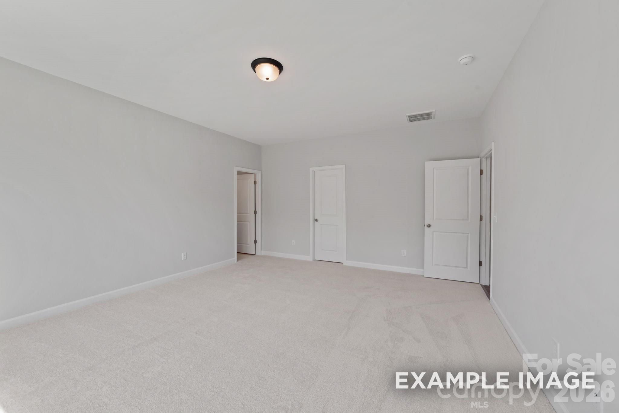 Spacious carpeted bedroom with neutral walls in The Magnolia B floor plan at Windgate in Mooresville, North Carolina.