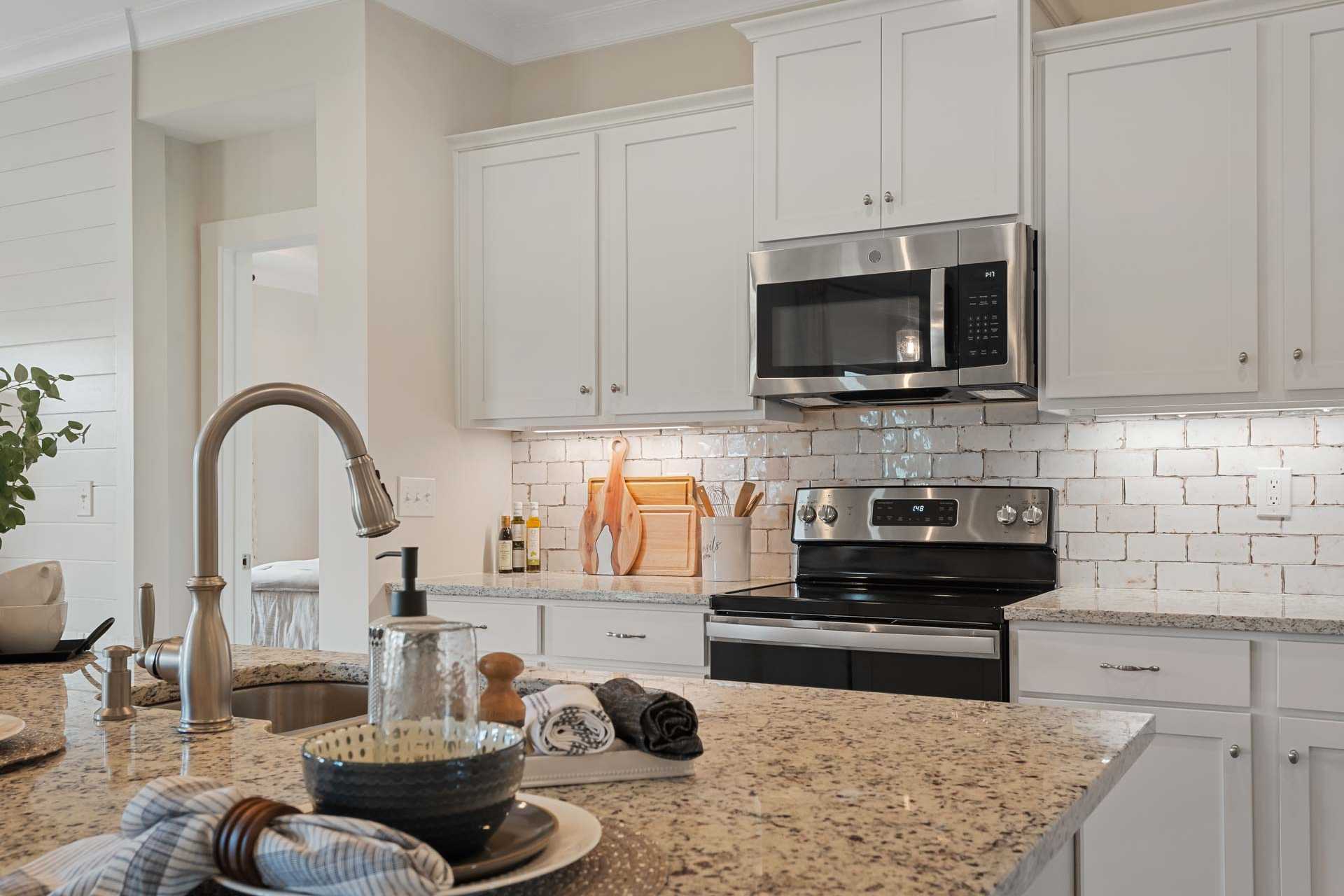 Modern kitchen in Flint Meadows New Market Alabama with white shaker cabinets, stainless steel appliances, subway tile backsplash, granite counters
