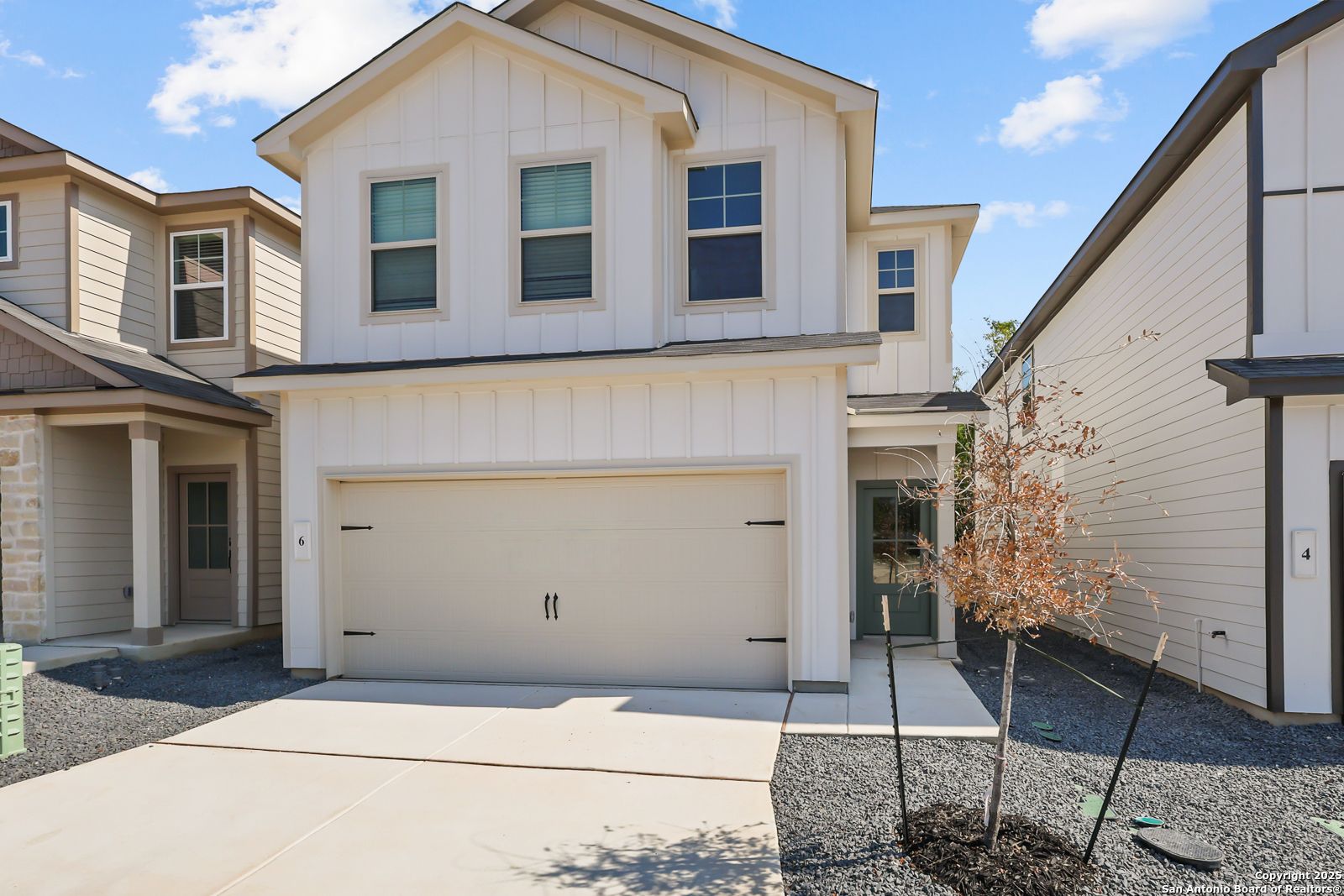 Modern two-story white board-and-batten home with two-car garage, driveway, and young trees in Cedar Heights, San Antonio, Texas - Davidson Homes The Gillian C