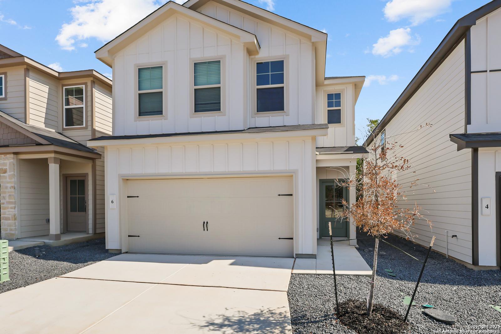 Modern two-story white board-and-batten home with two-car garage, driveway, and young trees in Cedar Heights, San Antonio, Texas - Davidson Homes The Gillian C