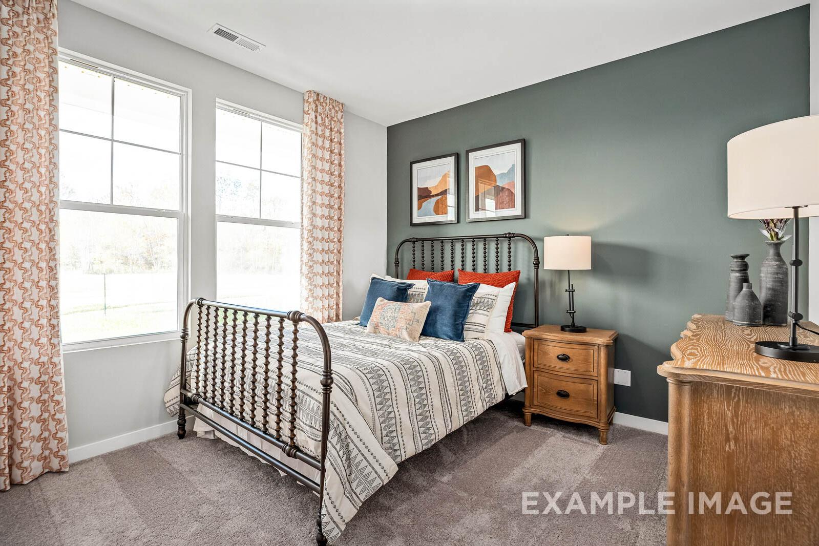 Cozy secondary bedroom in The Franklin B with wrought iron bed, sage green walls, wooden nightstand, and large curtained windows