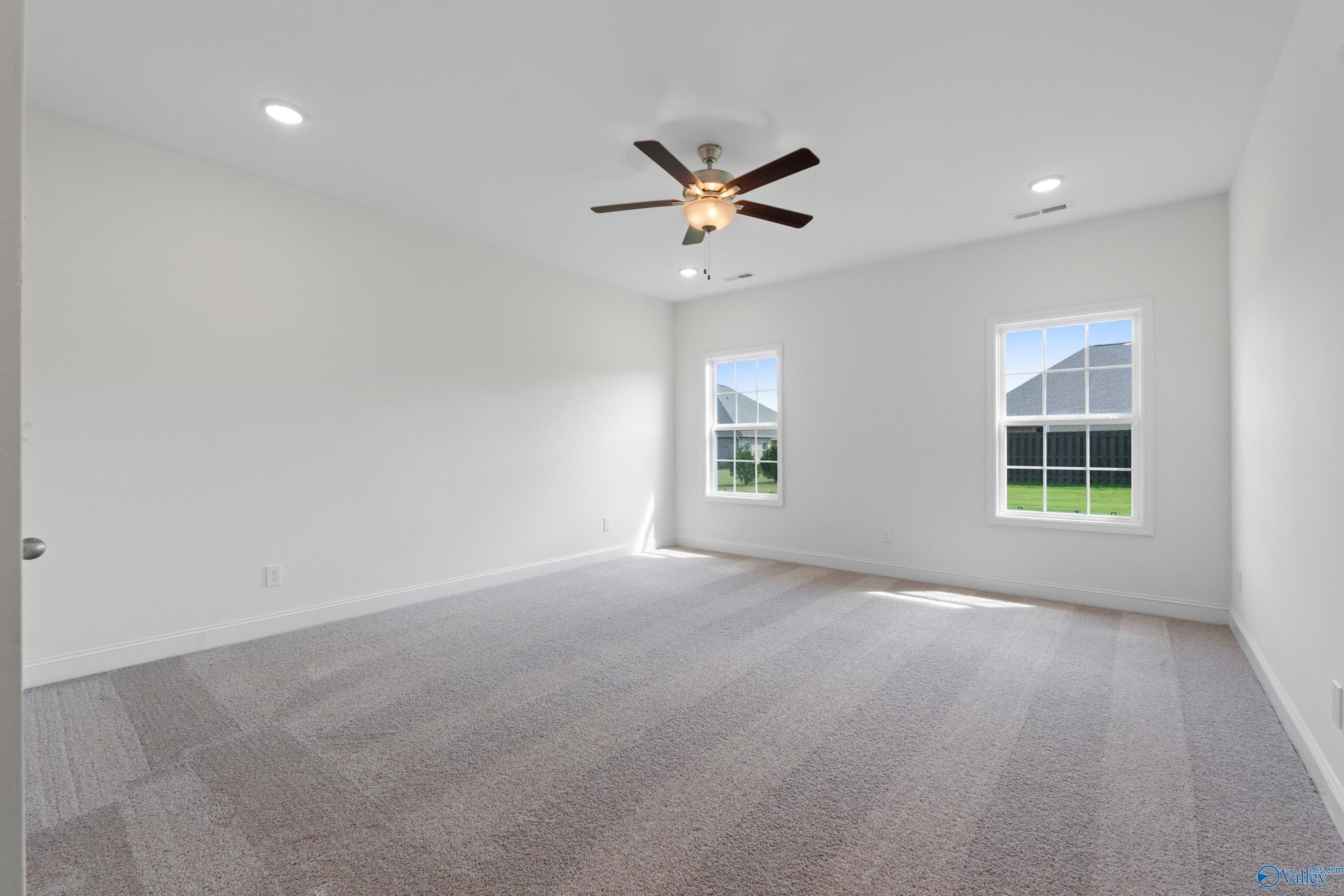 Bright secondary bedroom with ceiling fan, large windows, and carpeted floor in Davidson Homes The Rockford B, Toney, Alabama