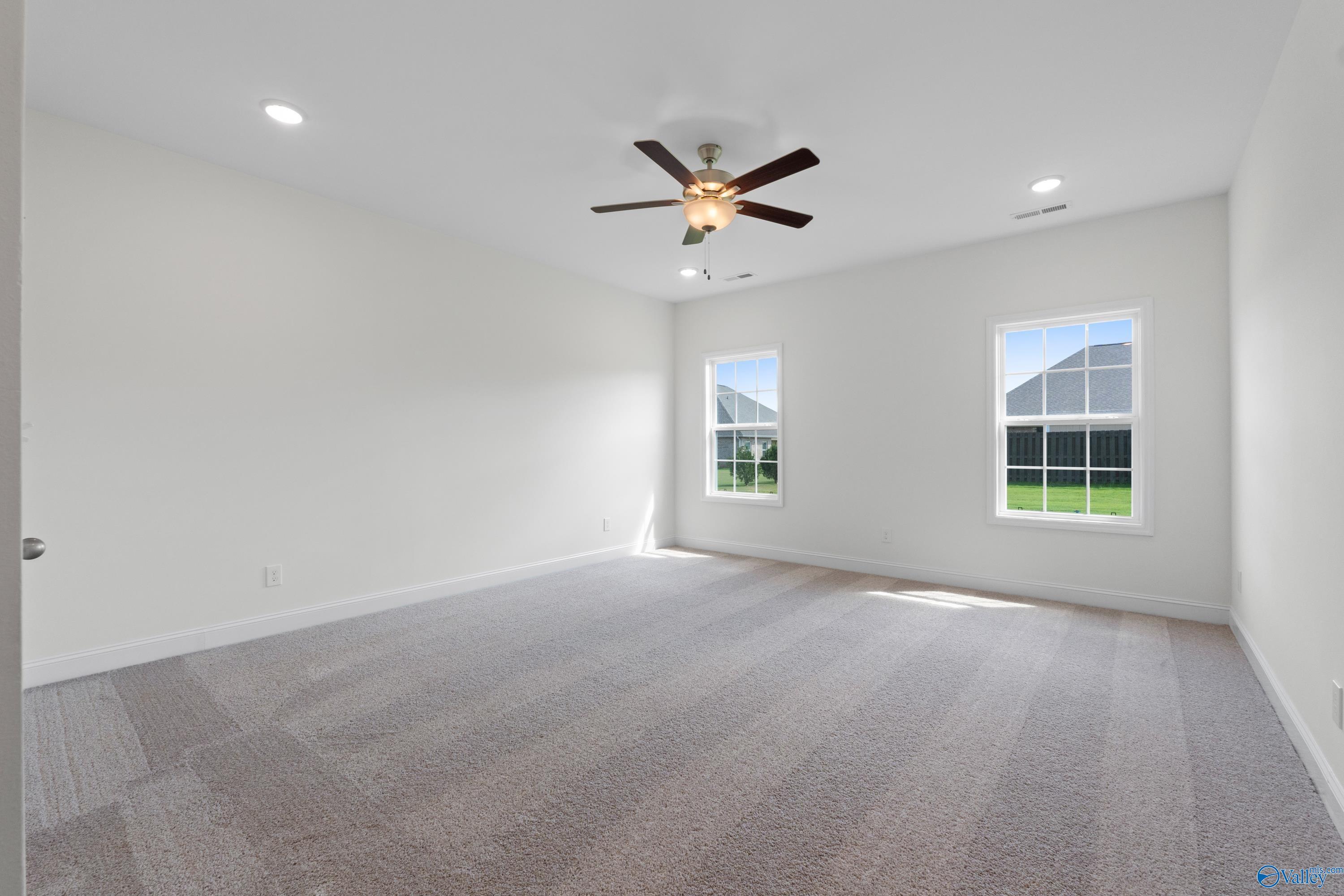 Bright secondary bedroom with ceiling fan, large windows, and carpeted floor in Davidson Homes The Rockford B, Toney, Alabama